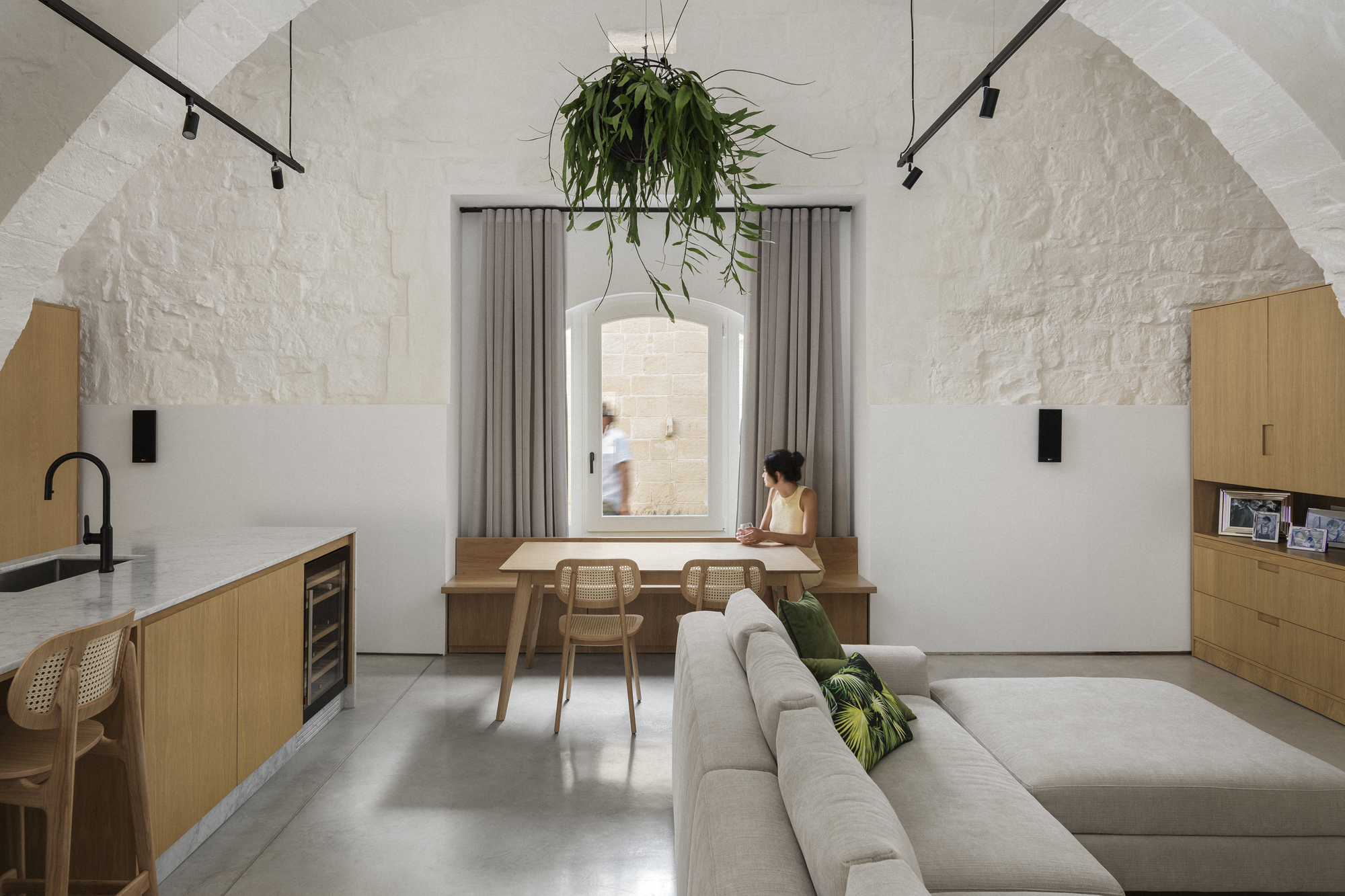Open living space with hanging planter suspended above a desk positioned in a recessed window alcove