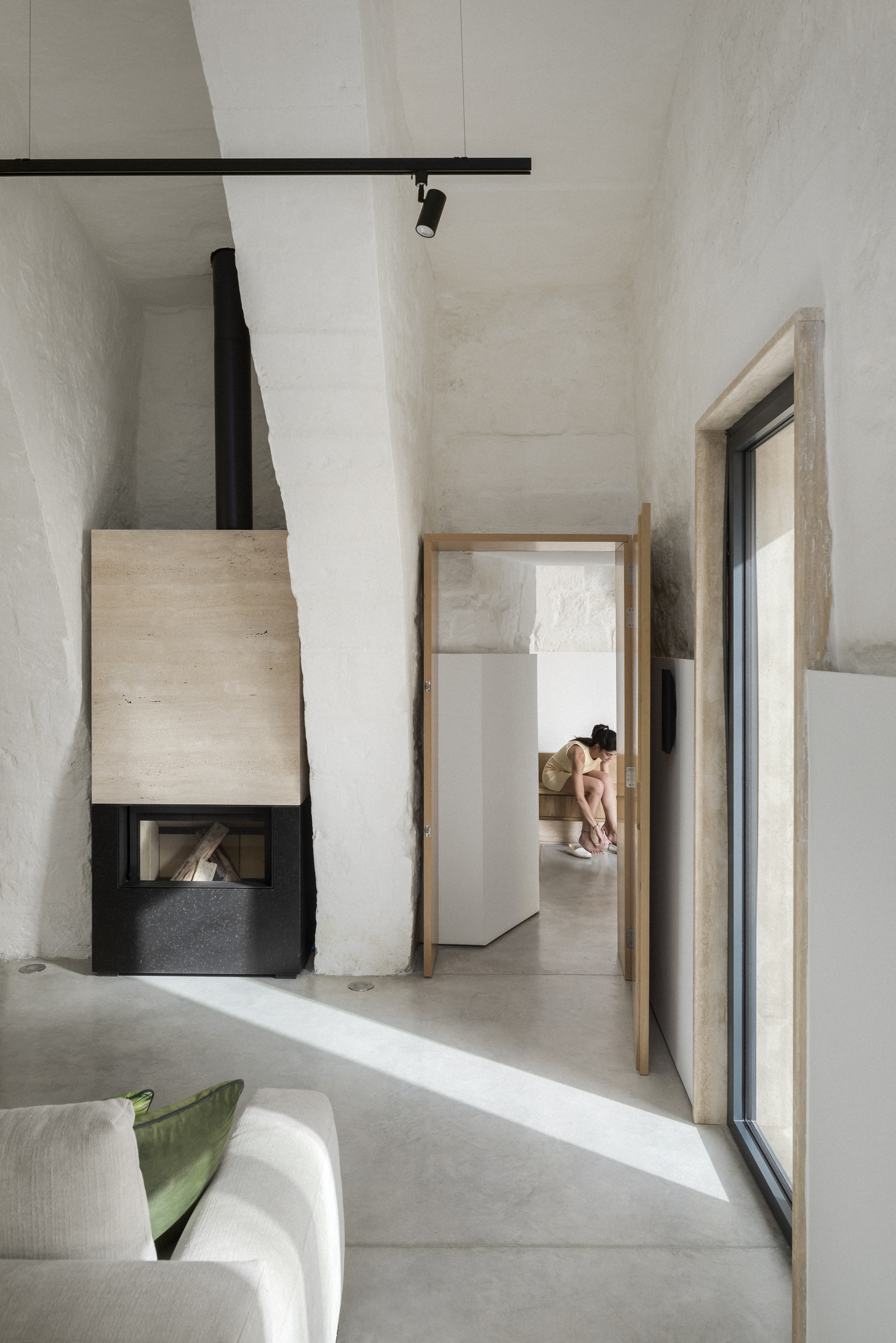 Corner fireplace with black metal hood and timber surround framing a view through an open doorway