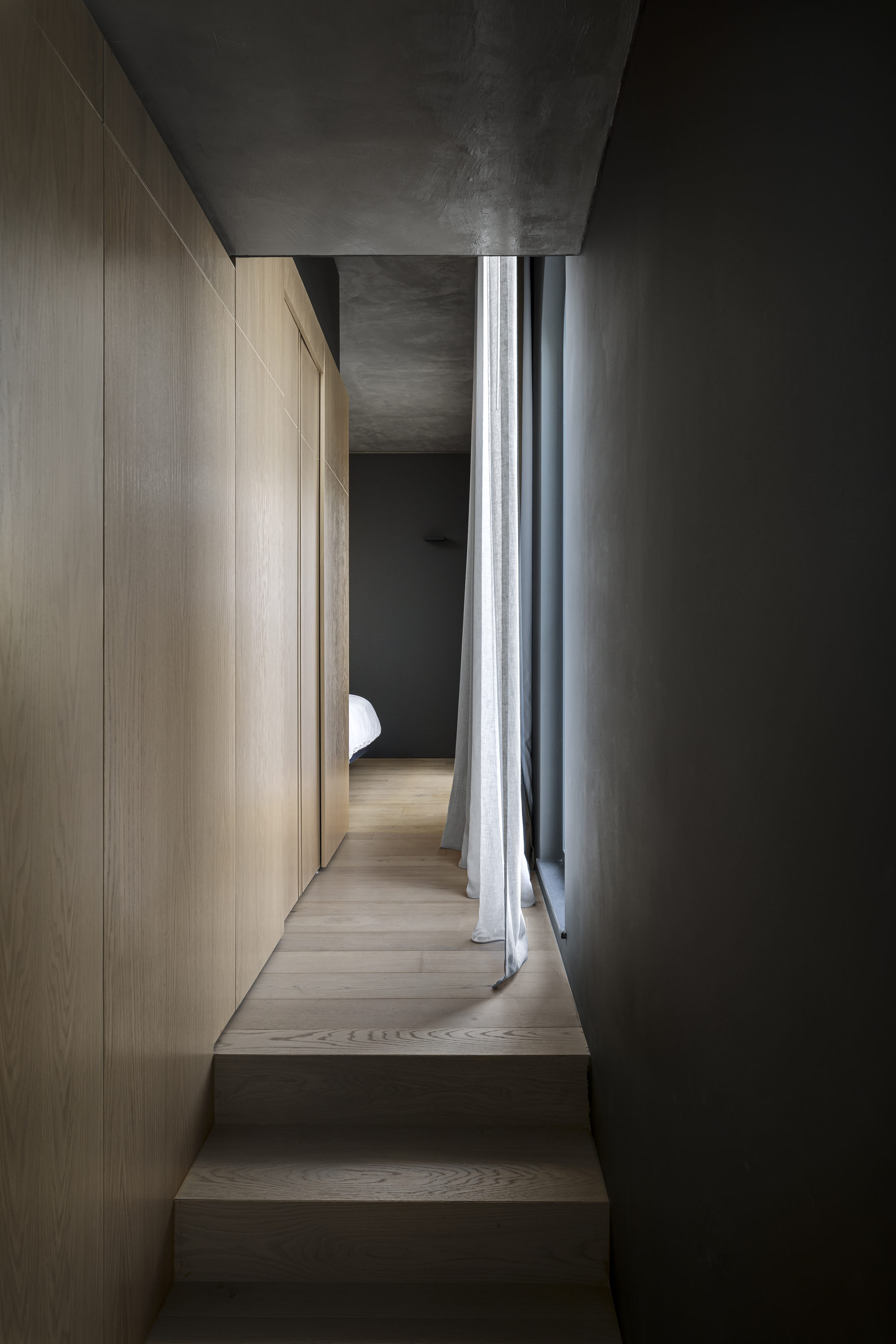 Narrow hallway with timber steps, oak paneling and grey curtains filtering daylight