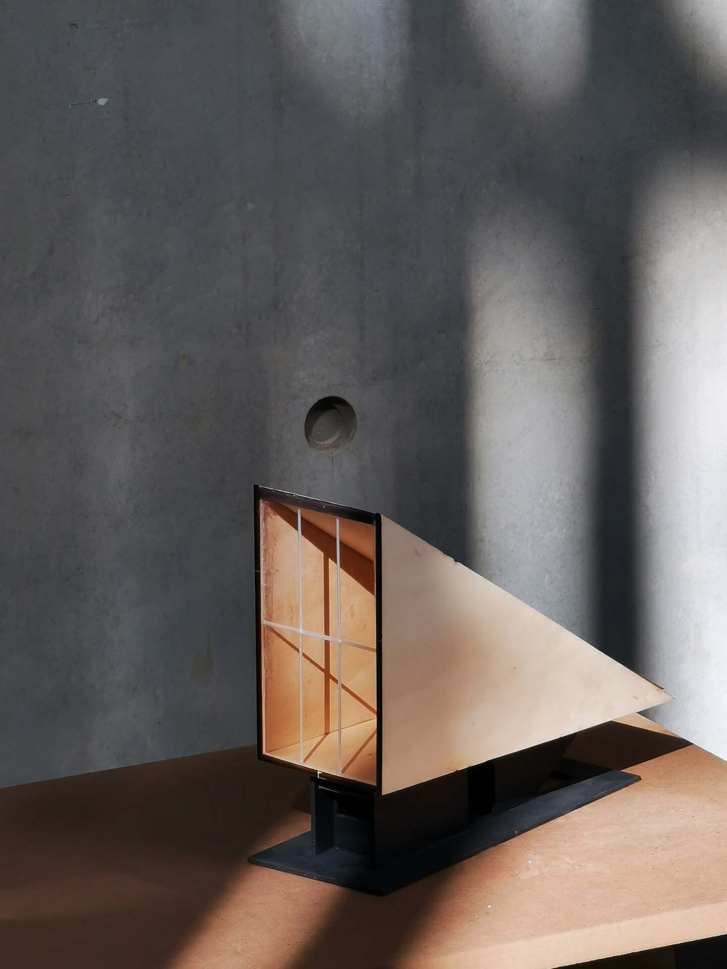 Polished concrete wall with angled daylight falling across a geometric glass door and steps