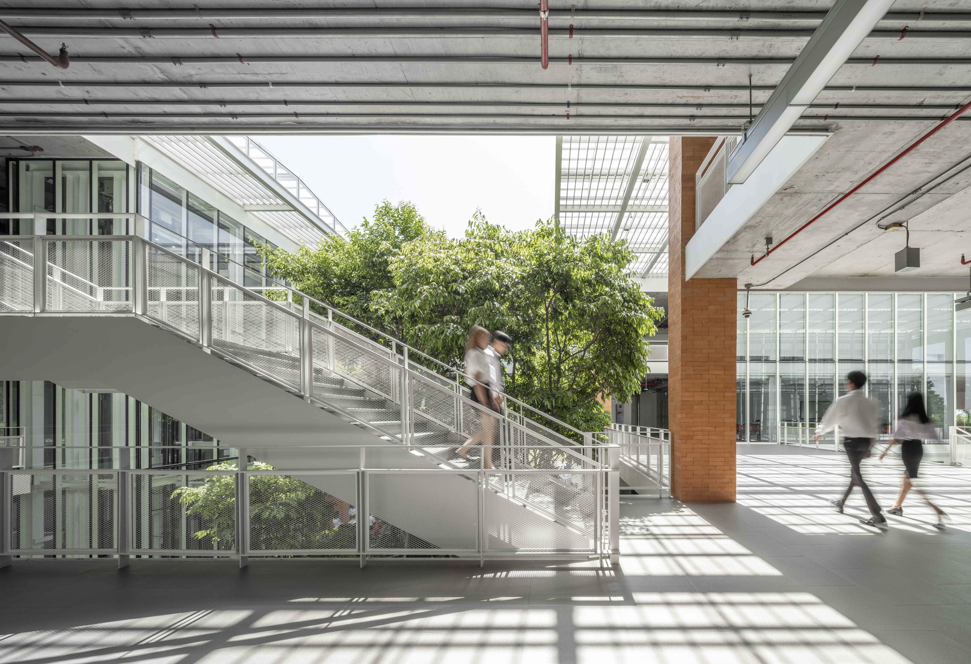 Interior circulation stair with students ascending beneath exposed concrete ceiling and skylights