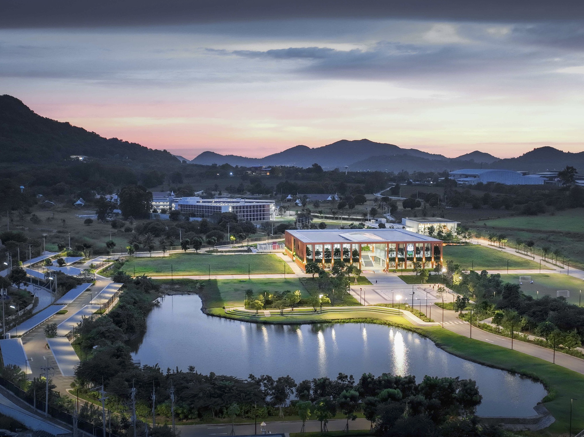 Dusk view of the illuminated complex beside a reflecting pond with mountain silhouettes beyond