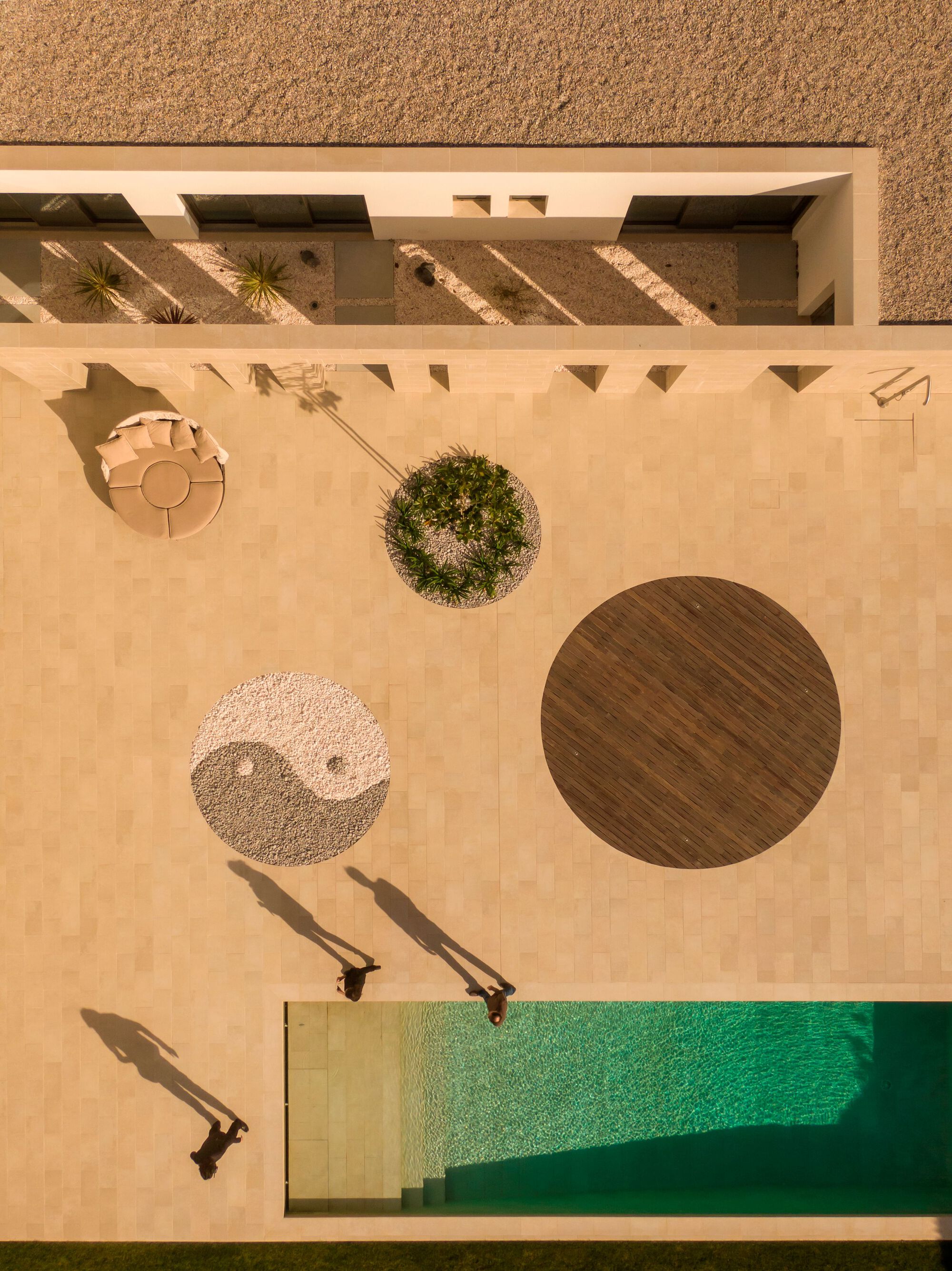 Overhead view of terrace showing circular planters timber deck and pool corner casting afternoon shadows