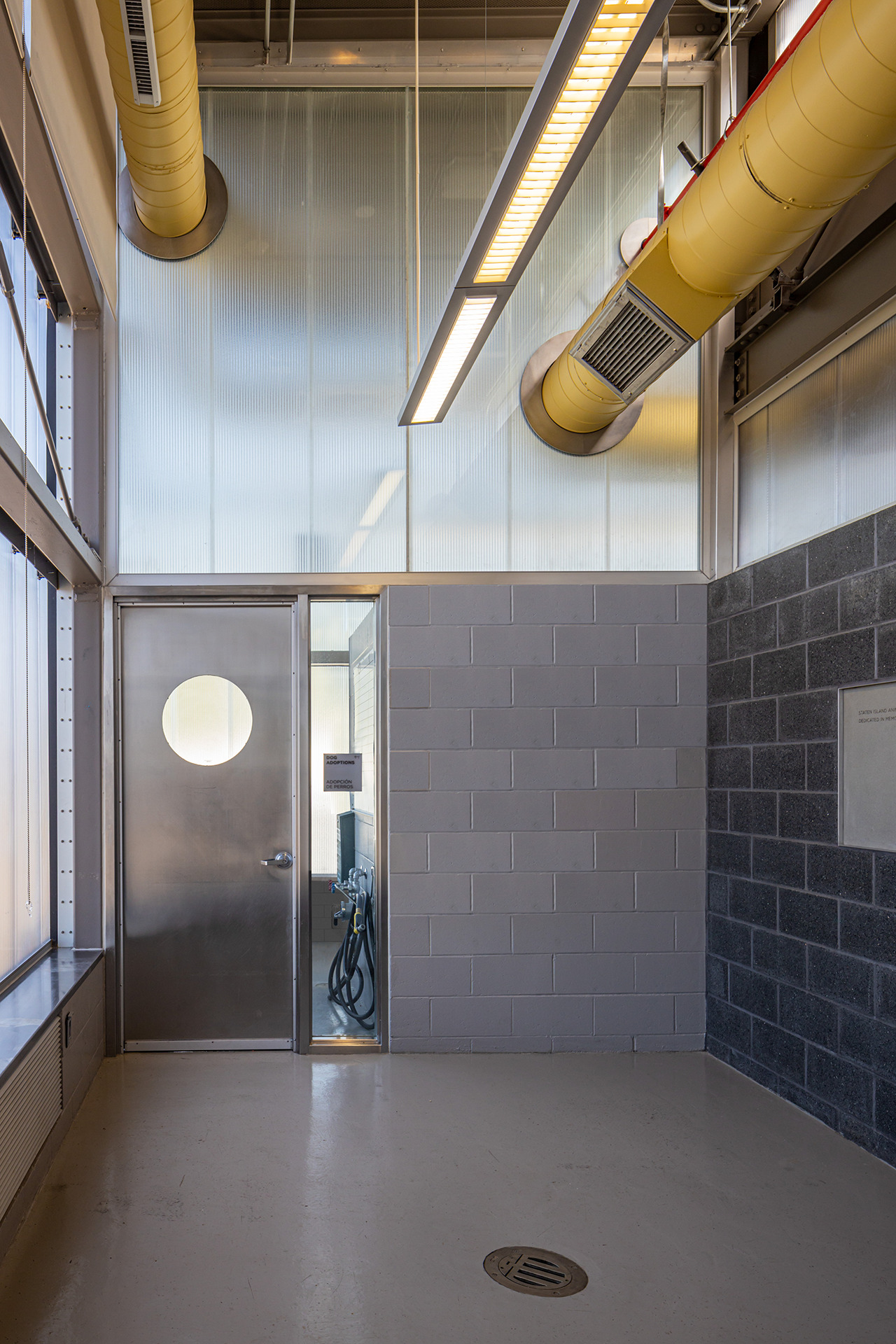 Interior corridor with exposed yellow ductwork, concrete masonry walls and circular porthole door