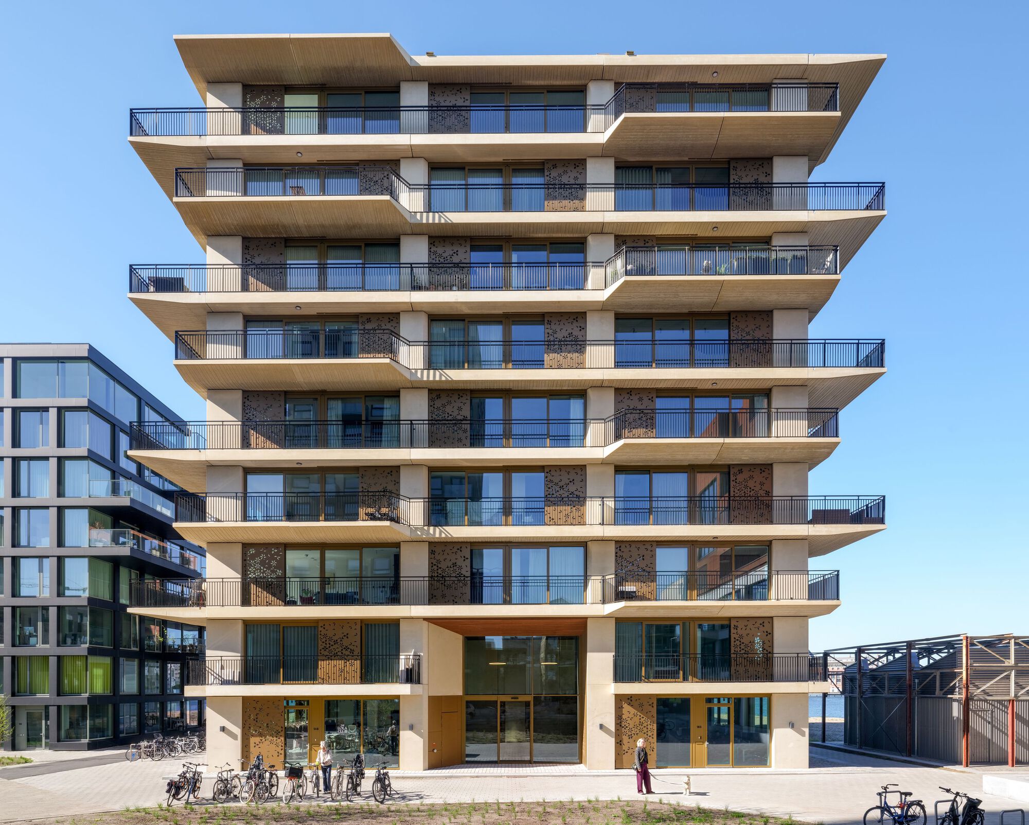 Frontal view of the multi-story residential facade with deep cantilevered balconies and bicycles parked at ground level
