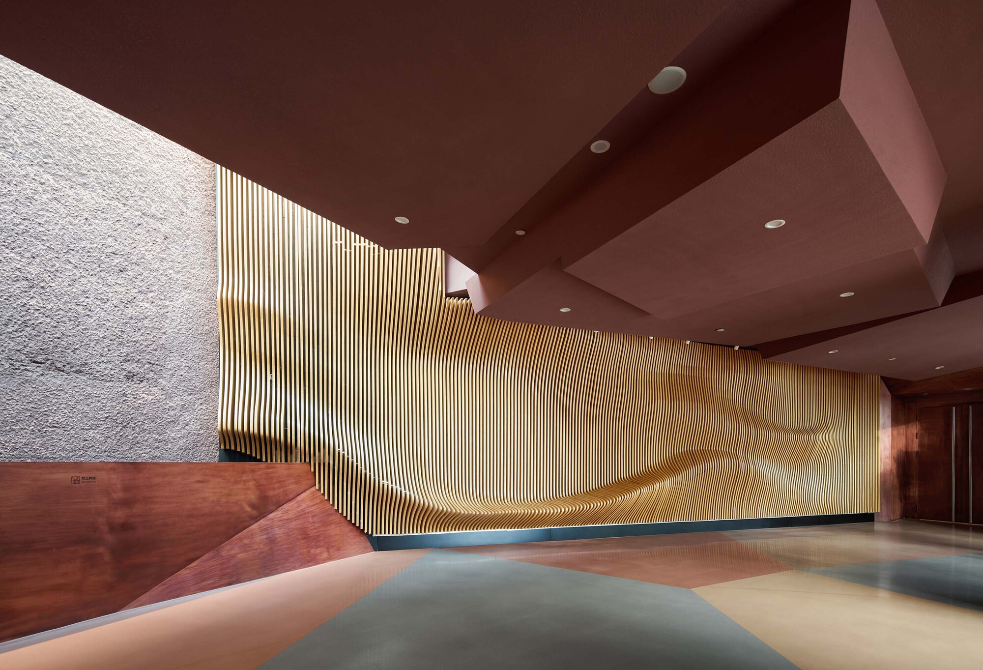 Interior lobby with vertical timber screen wall and angular red-brown ceiling planes