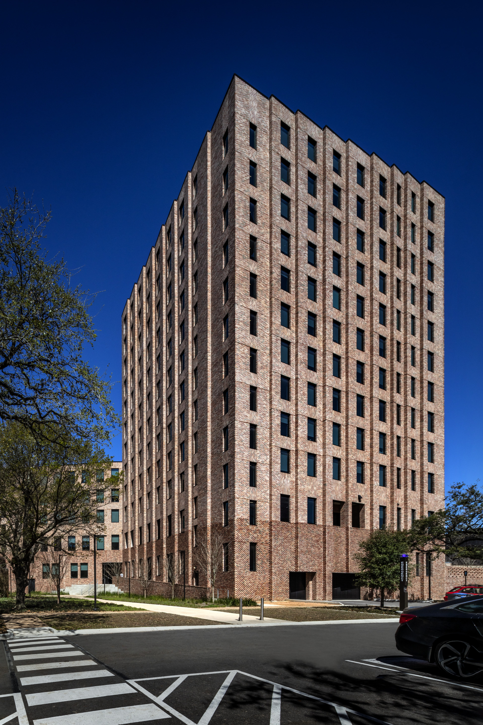 Brick tower facade with vertical window pattern against a deep blue sky