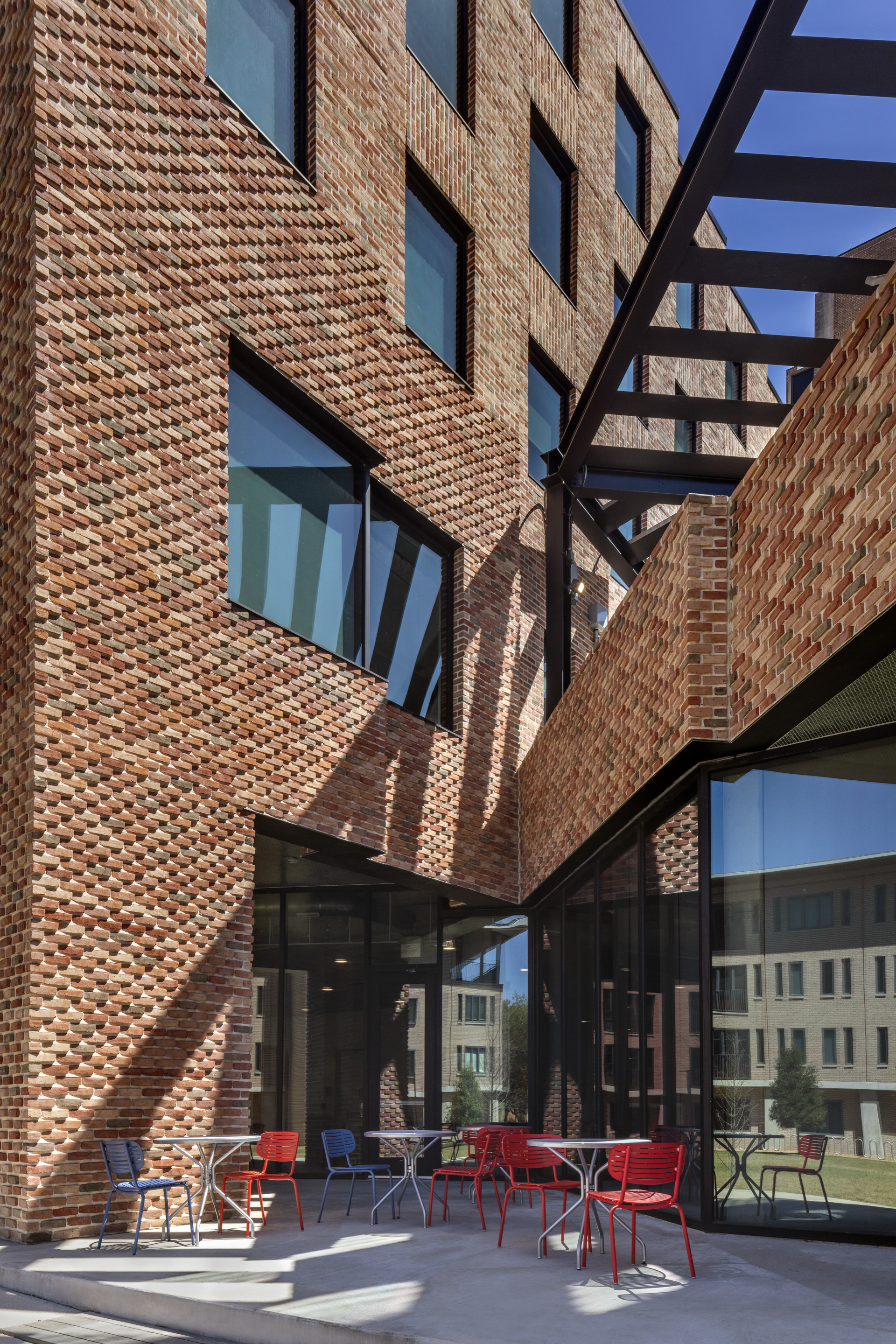 Courtyard looking up at textured brick walls with steel bridge element crossing overhead in late afternoon light