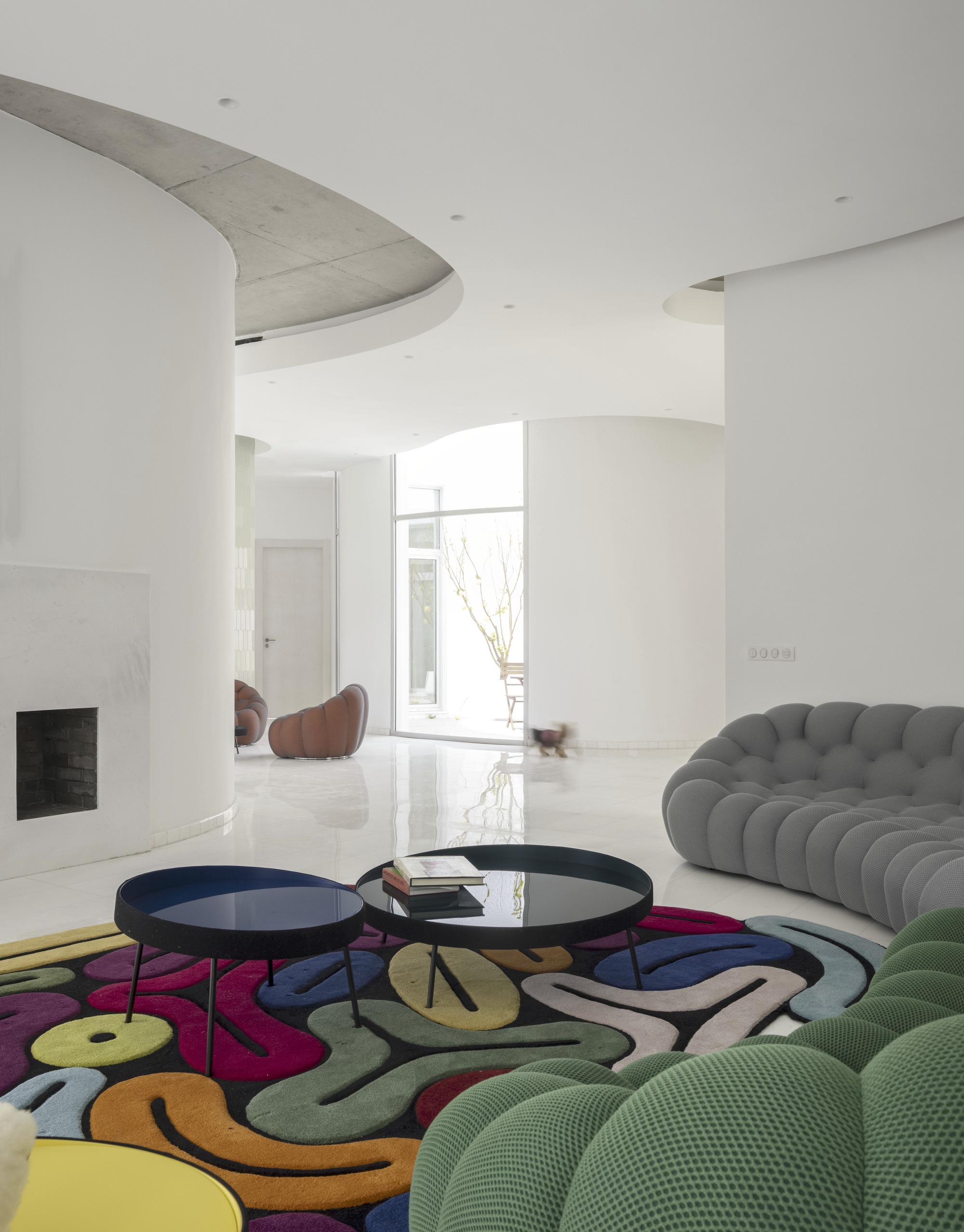 Living room with curved concrete ceiling forms and a patterned rug under bright daylight