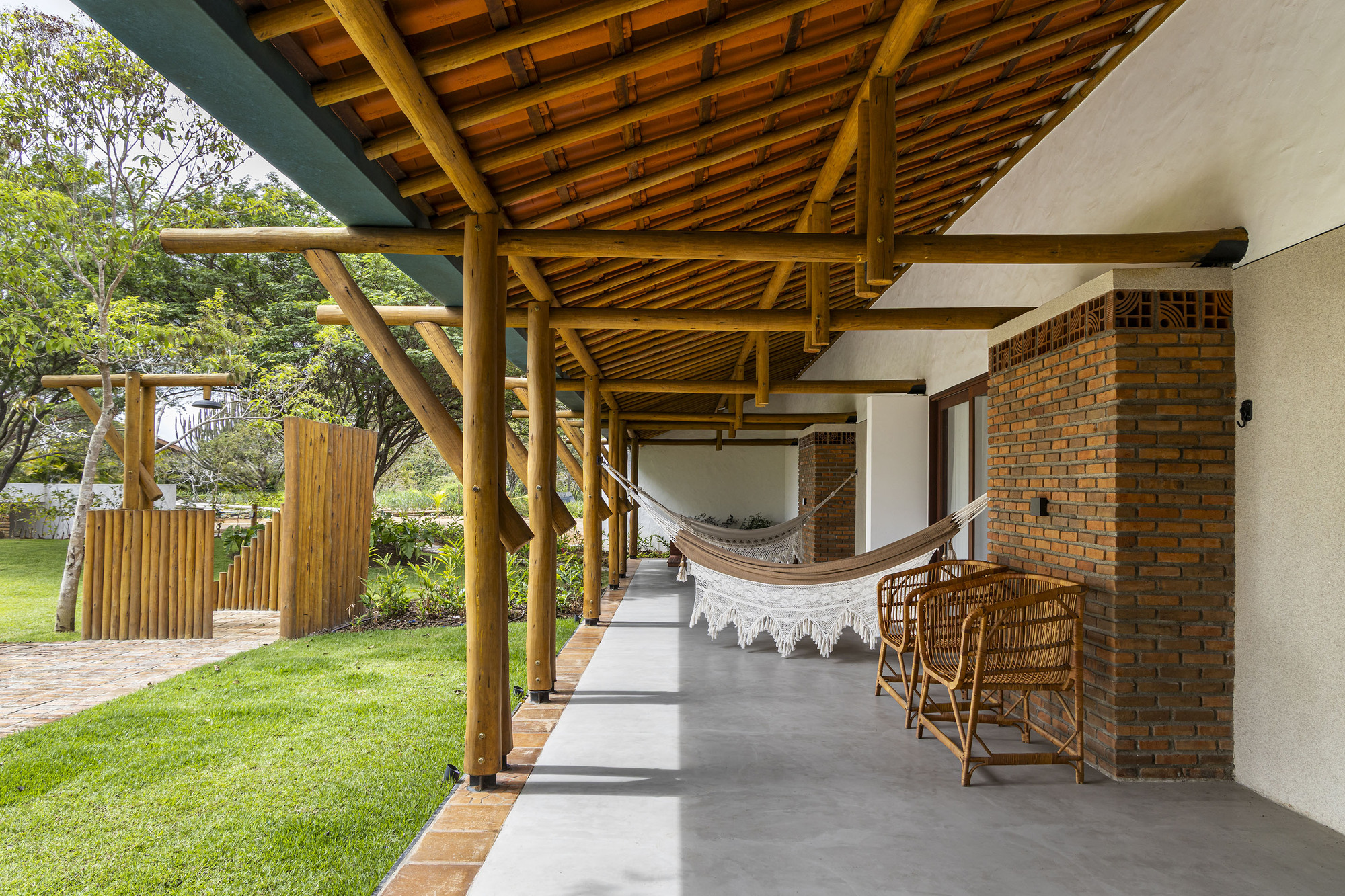 Covered terrace with exposed timber ceiling, concrete floor and hammock looking toward the lawn