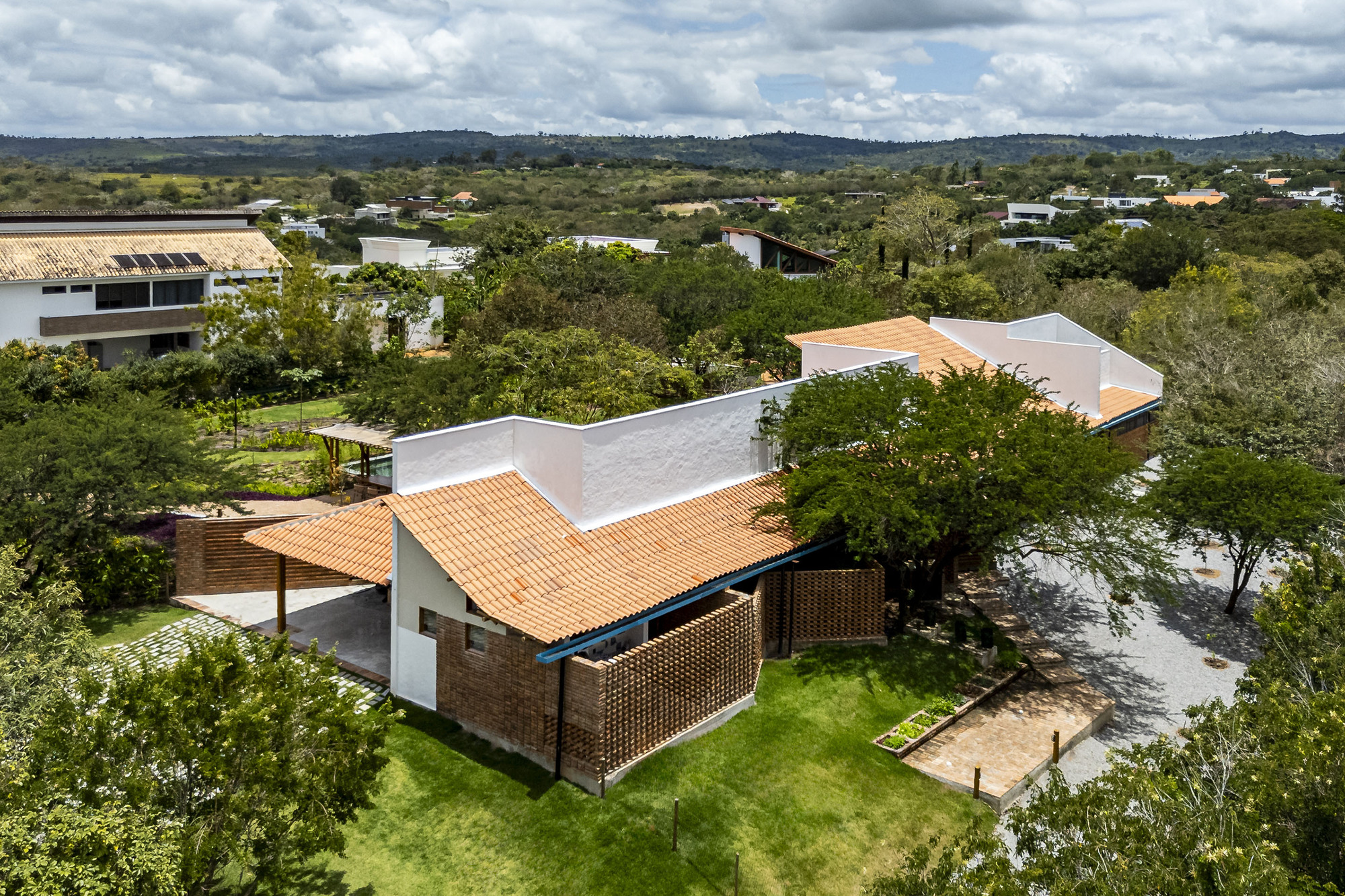 Aerial perspective of interlocking orange tile roof volumes with perforated brick screen and courtyard
