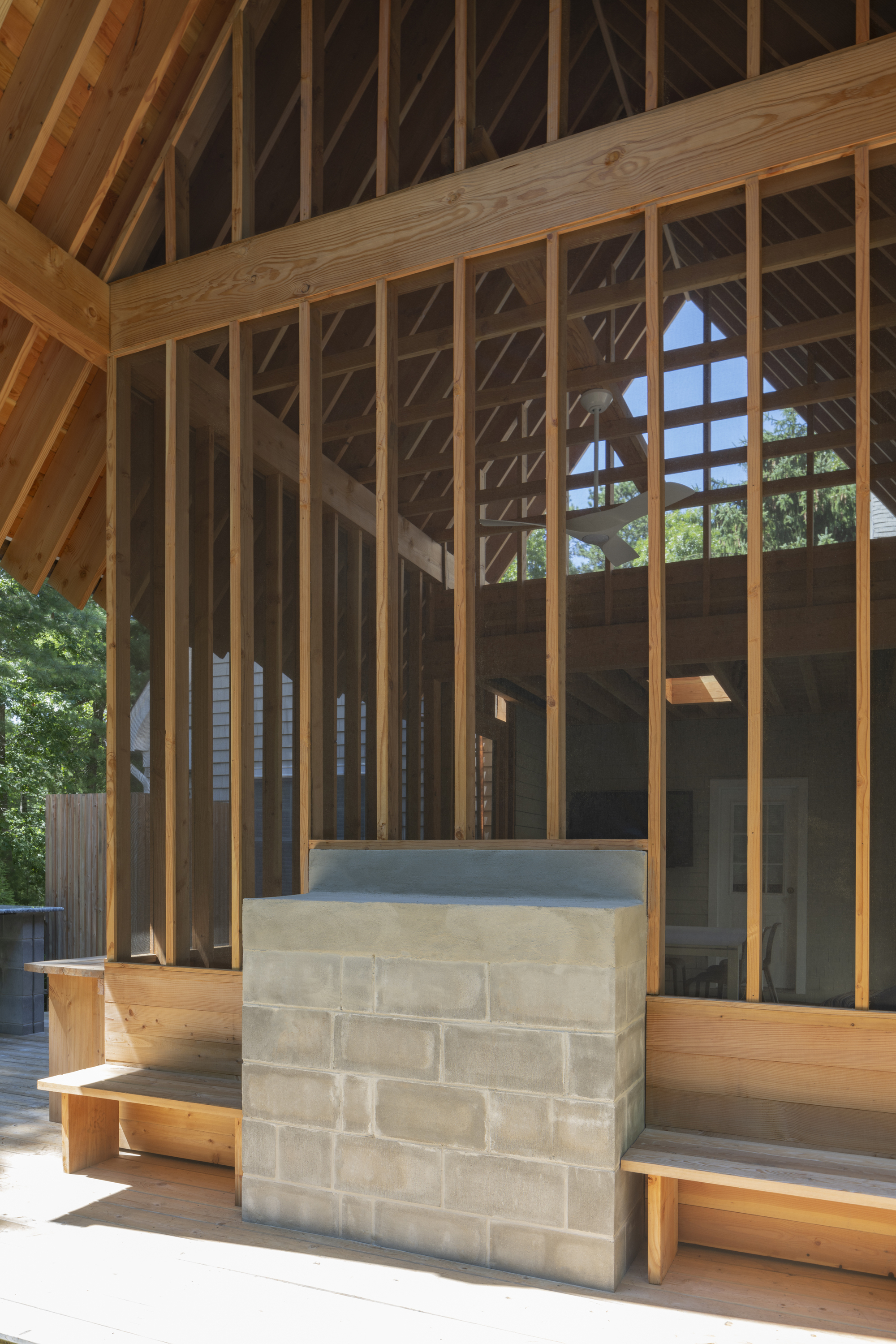 Detail of concrete block bench flanked by timber posts beneath the gabled roof structure