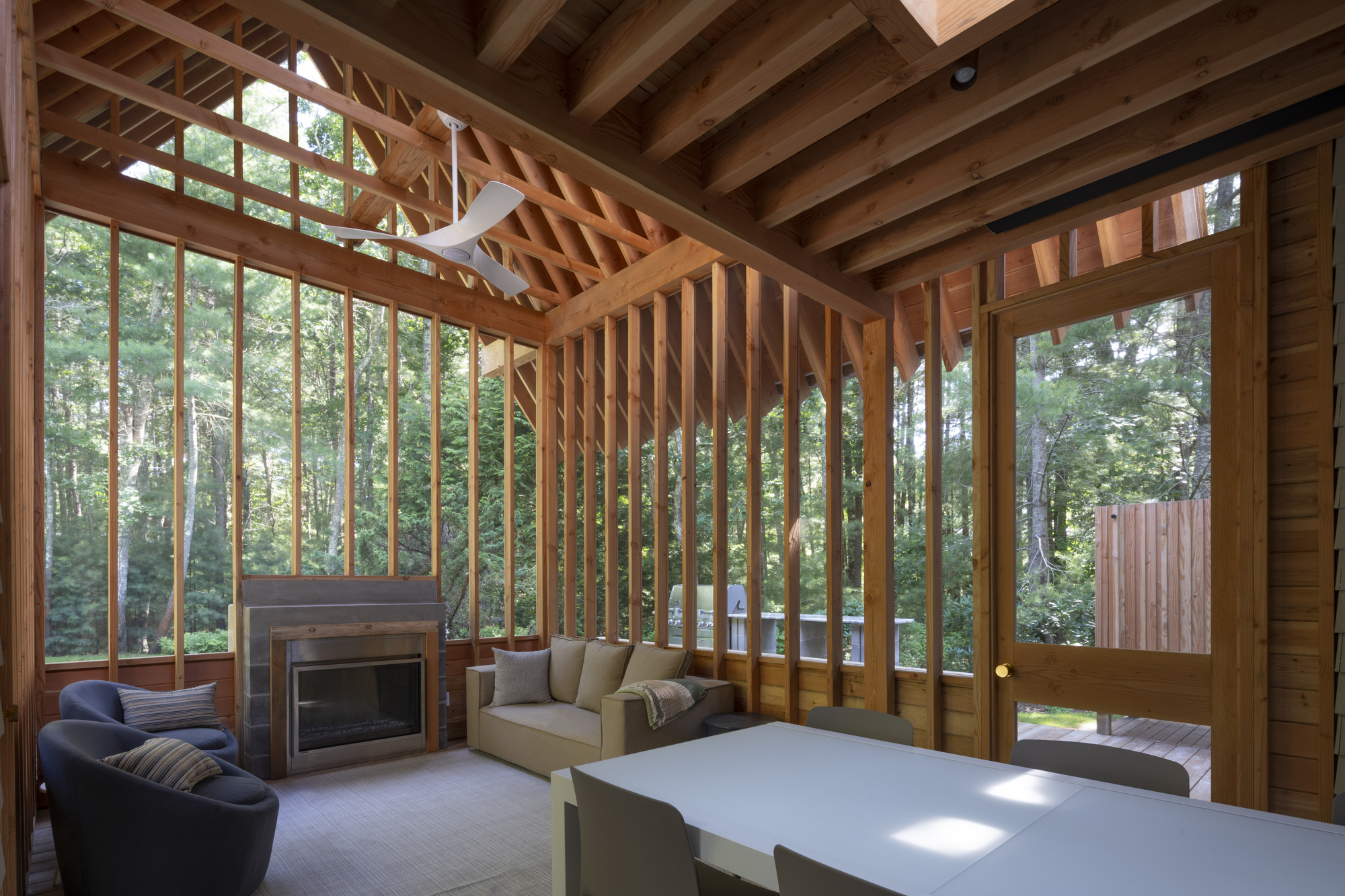 Interior with exposed timber rafters and vertical screen framing a fireplace and seating area