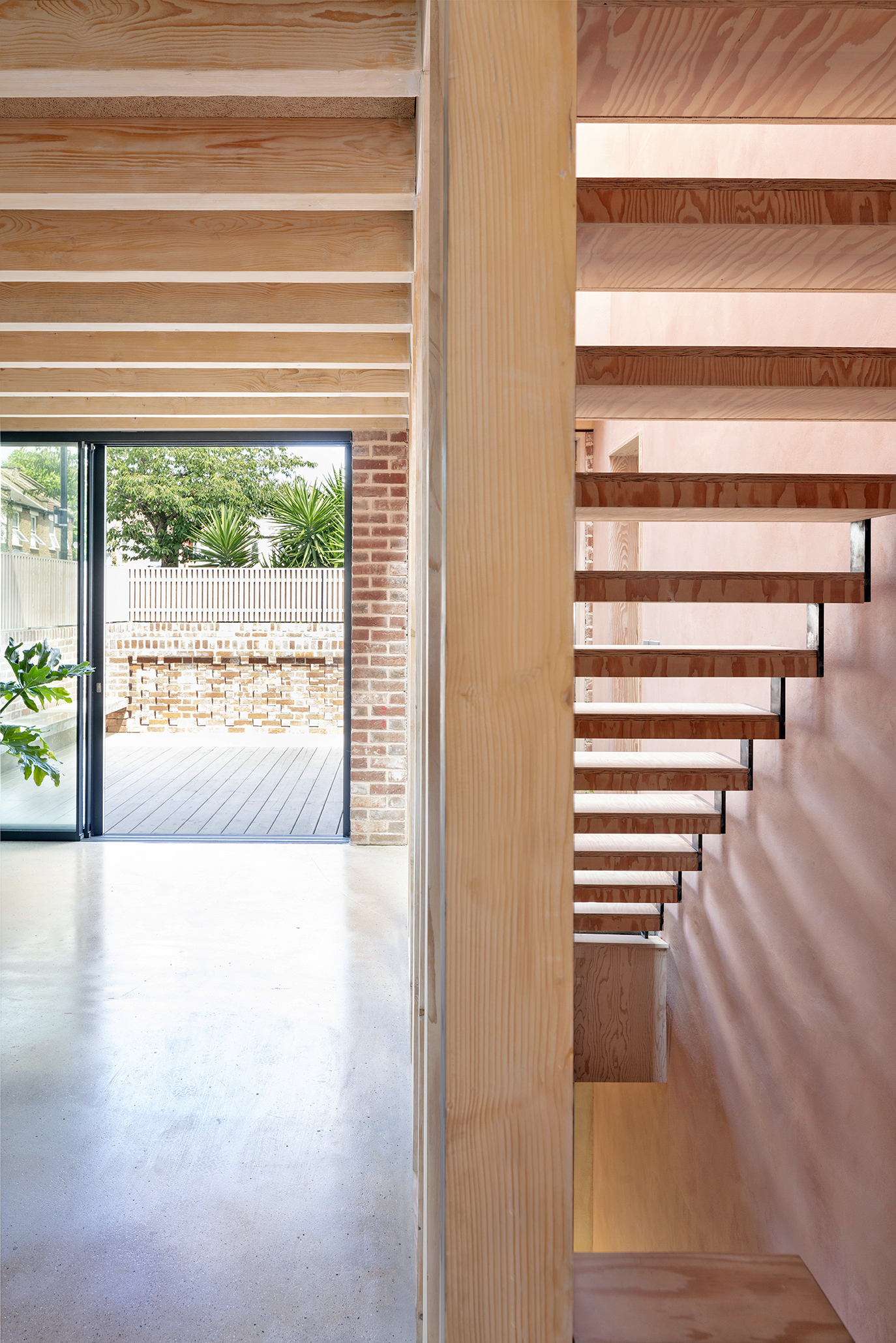 Timber open-tread staircase beside a glazed door leading to a timber-decked courtyard