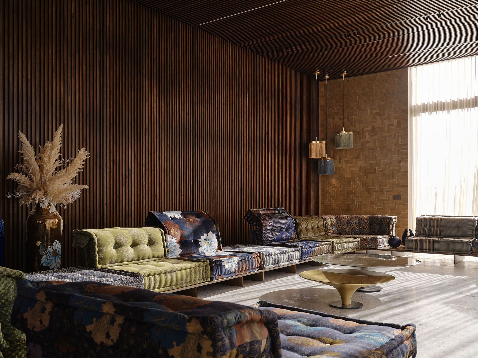 Lounge with timber slatted ceiling and pampas grass beside patterned upholstered seating