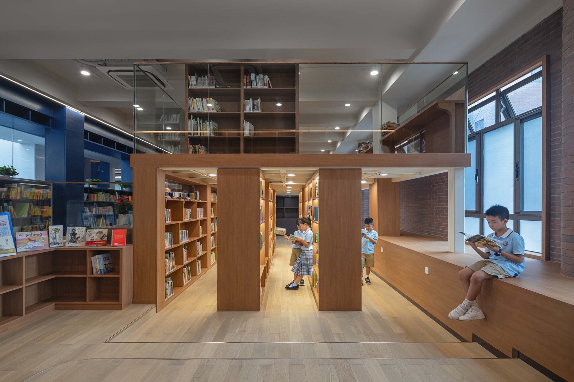 Library space with timber bookshelves and built-in window seating where students read during daytime