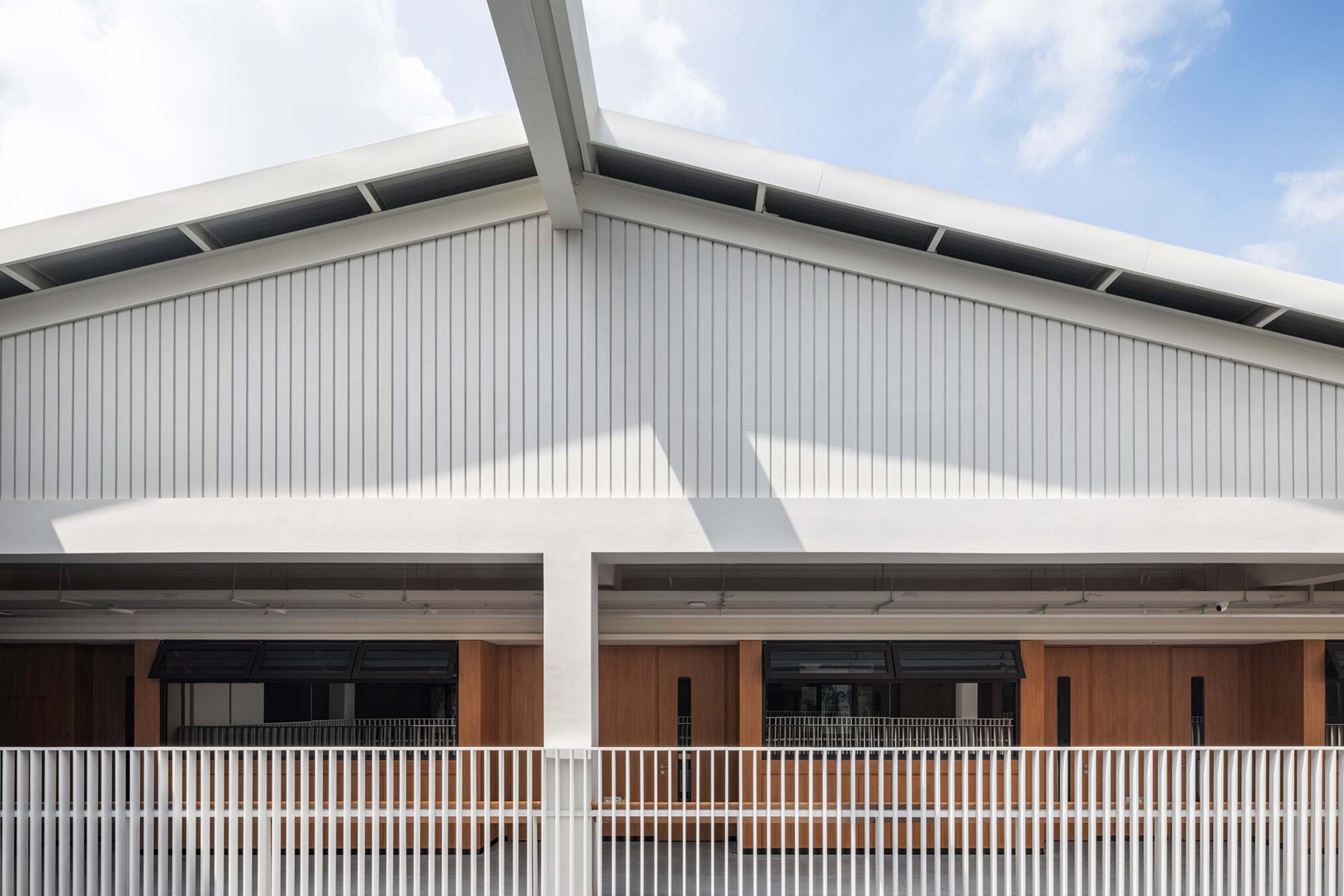 Gabled roof with vertical metal cladding above a covered walkway with white vertical balusters
