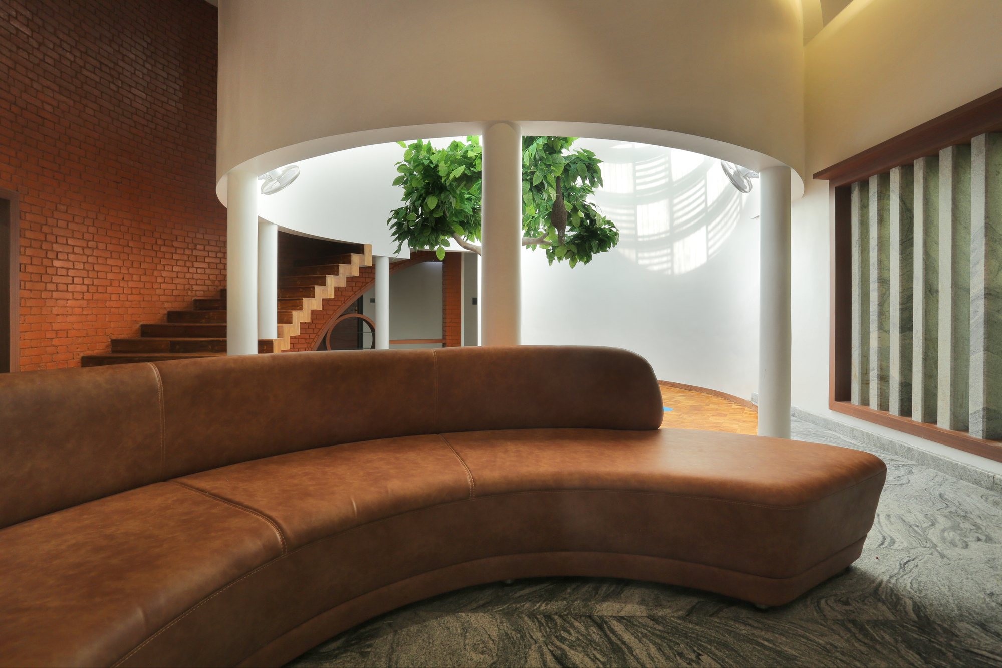 Curved leather sofa facing the central courtyard with white columns and brick stair wall beyond