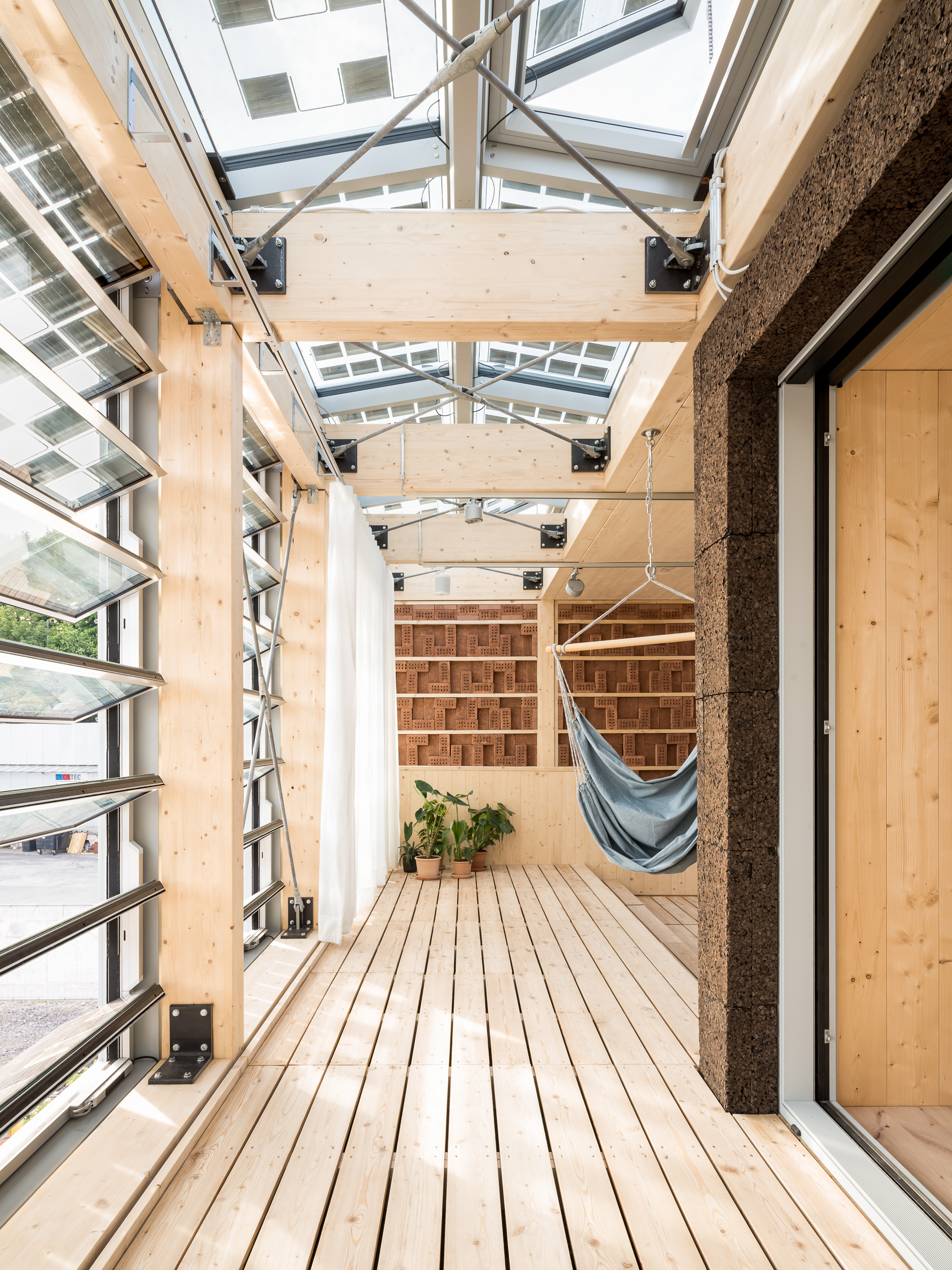 Covered deck with timber flooring, exposed roof beams and hammock beside cork-clad column