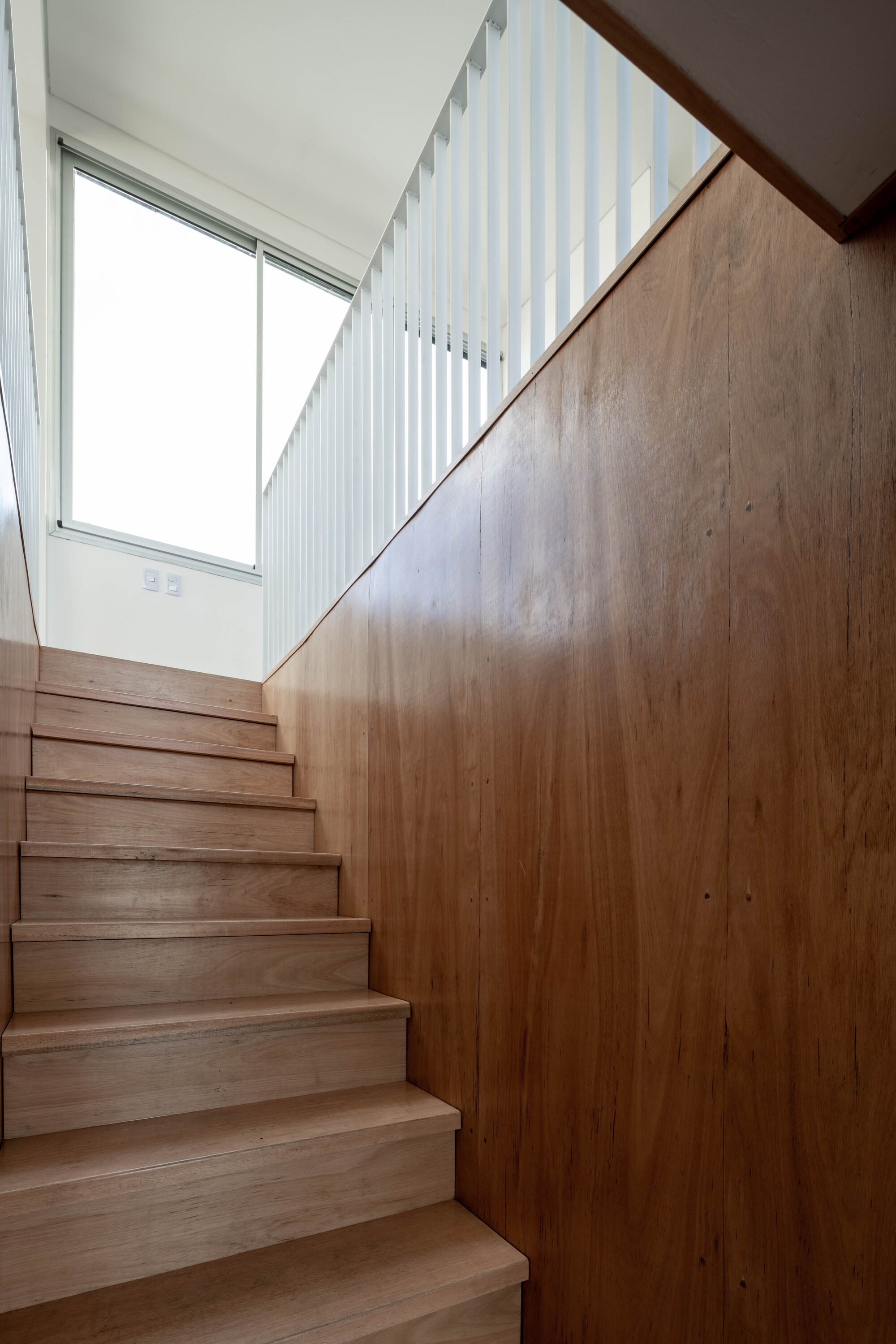 Timber staircase with vertical slatted screen and high clerestory window filtering natural light
