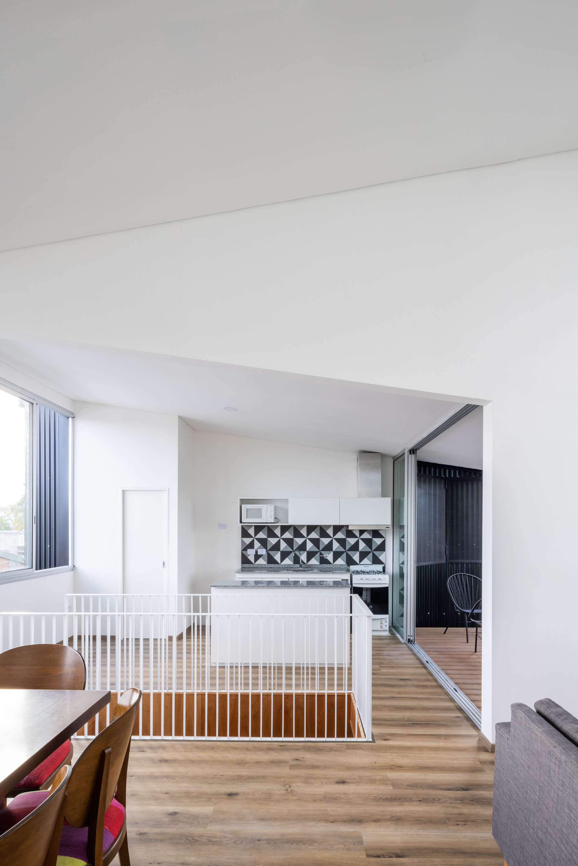 Interior view of open-plan living space with white vertical railings and geometric tiled credenza under natural light