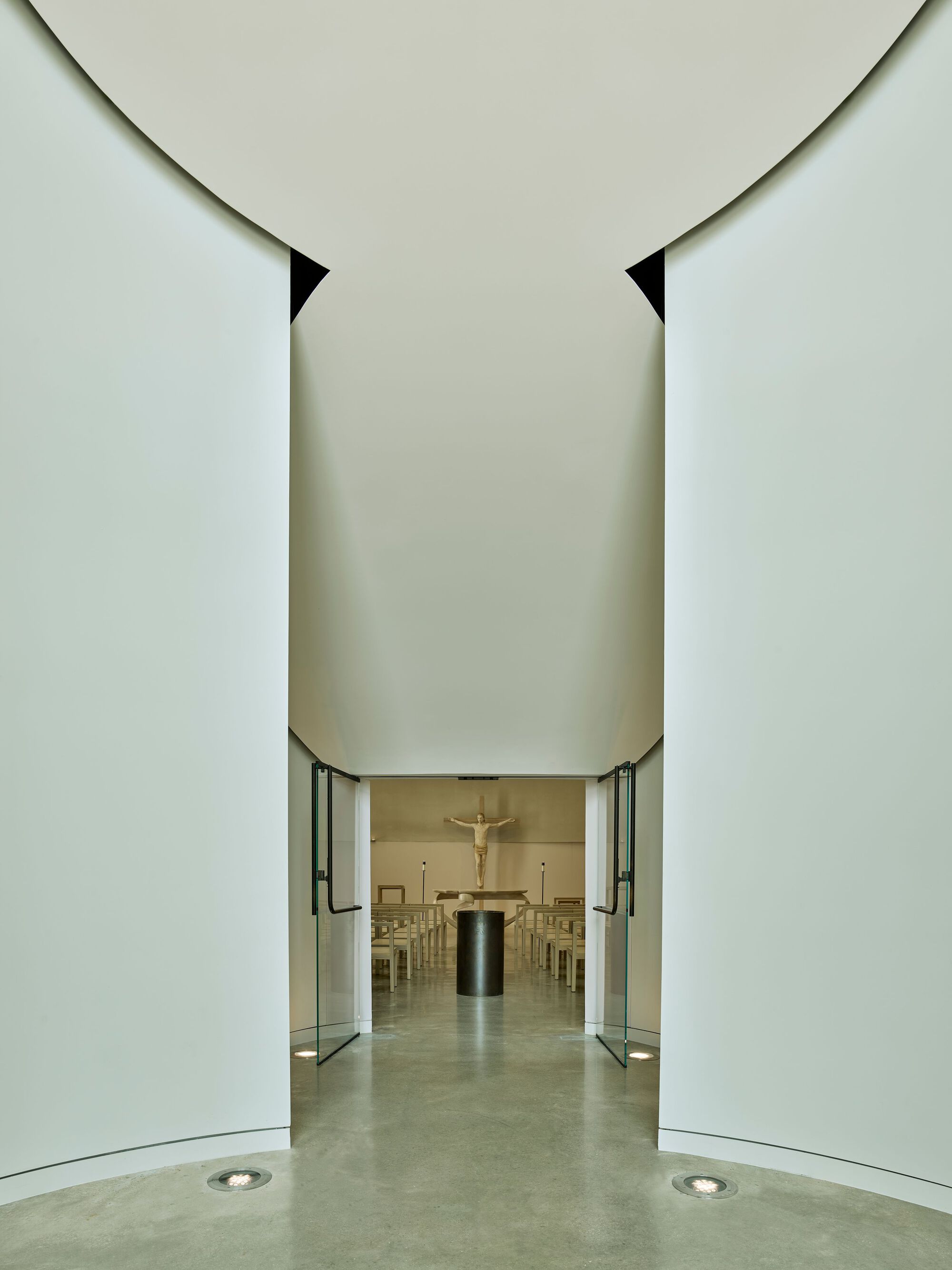View through the central entrance corridor toward the chapel altar with glass doors open