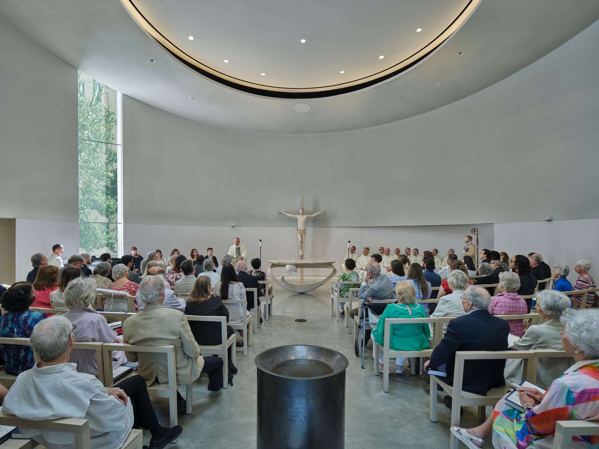 Congregation seated in the round sanctuary during a service beneath a circular skylight