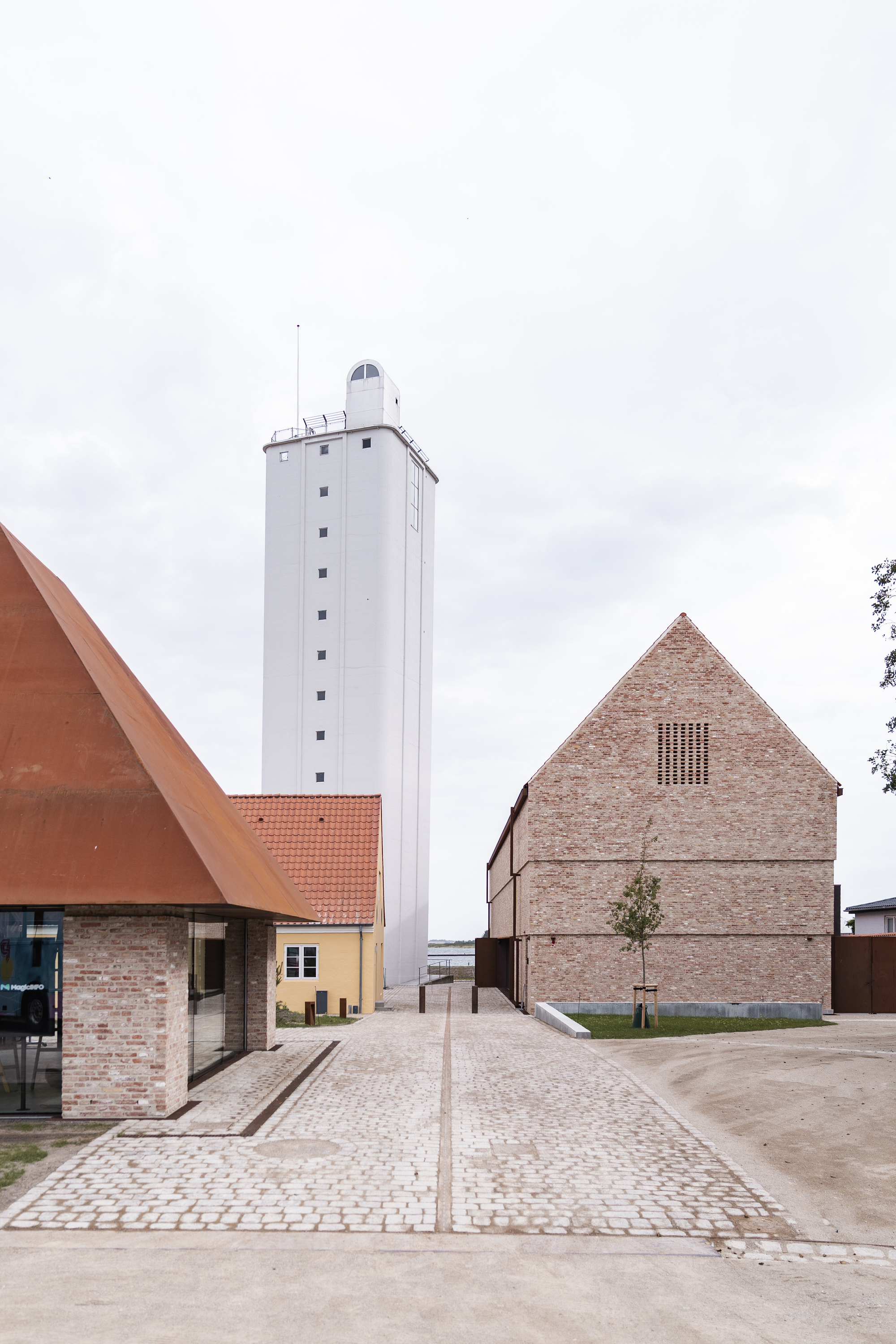 Plaza view showing white tower, brick gabled building, and low structures with terra cotta roofs