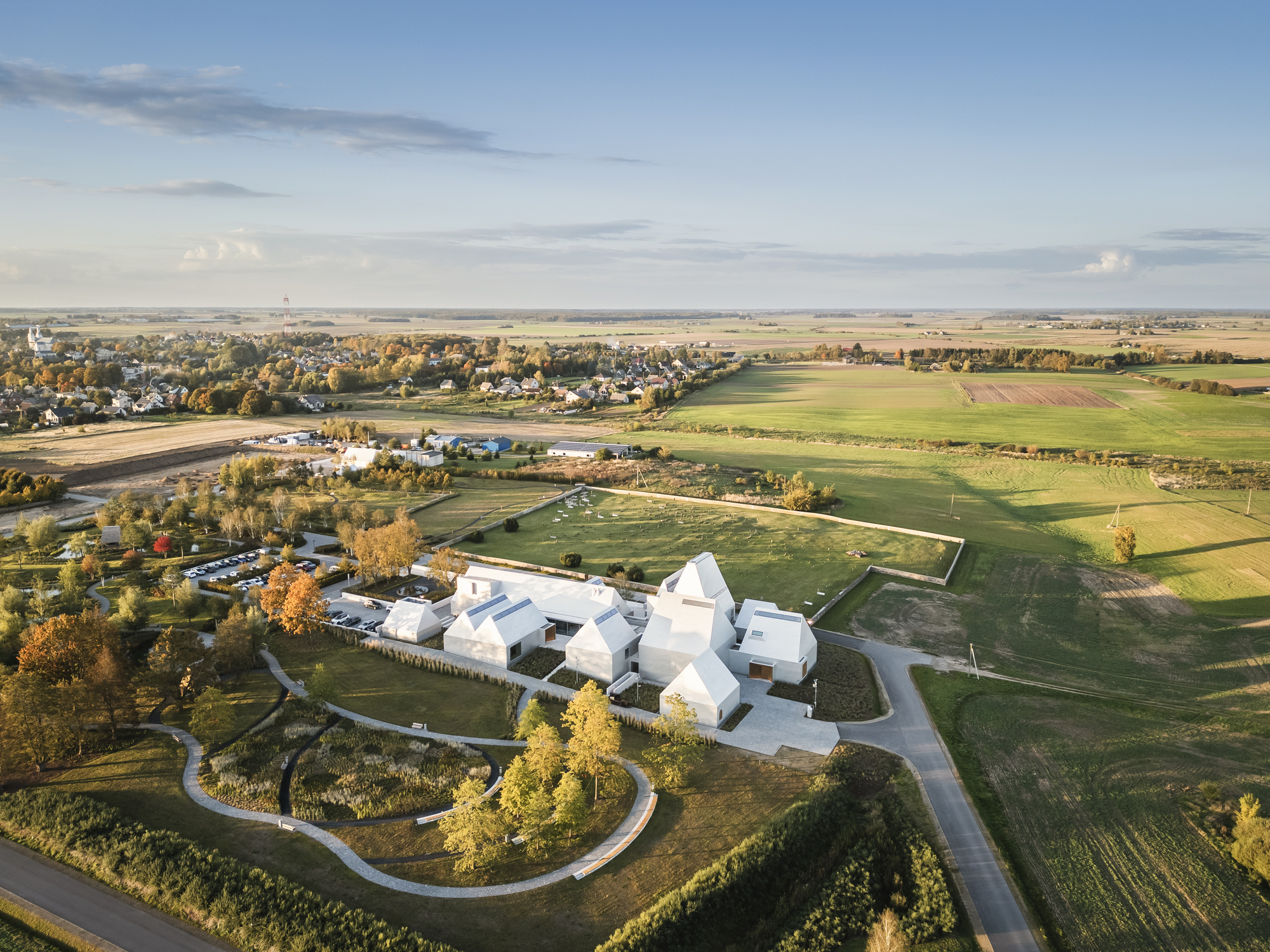 Aerial view of the white multi-lobed roof complex surrounded by agricultural fields and autumn trees