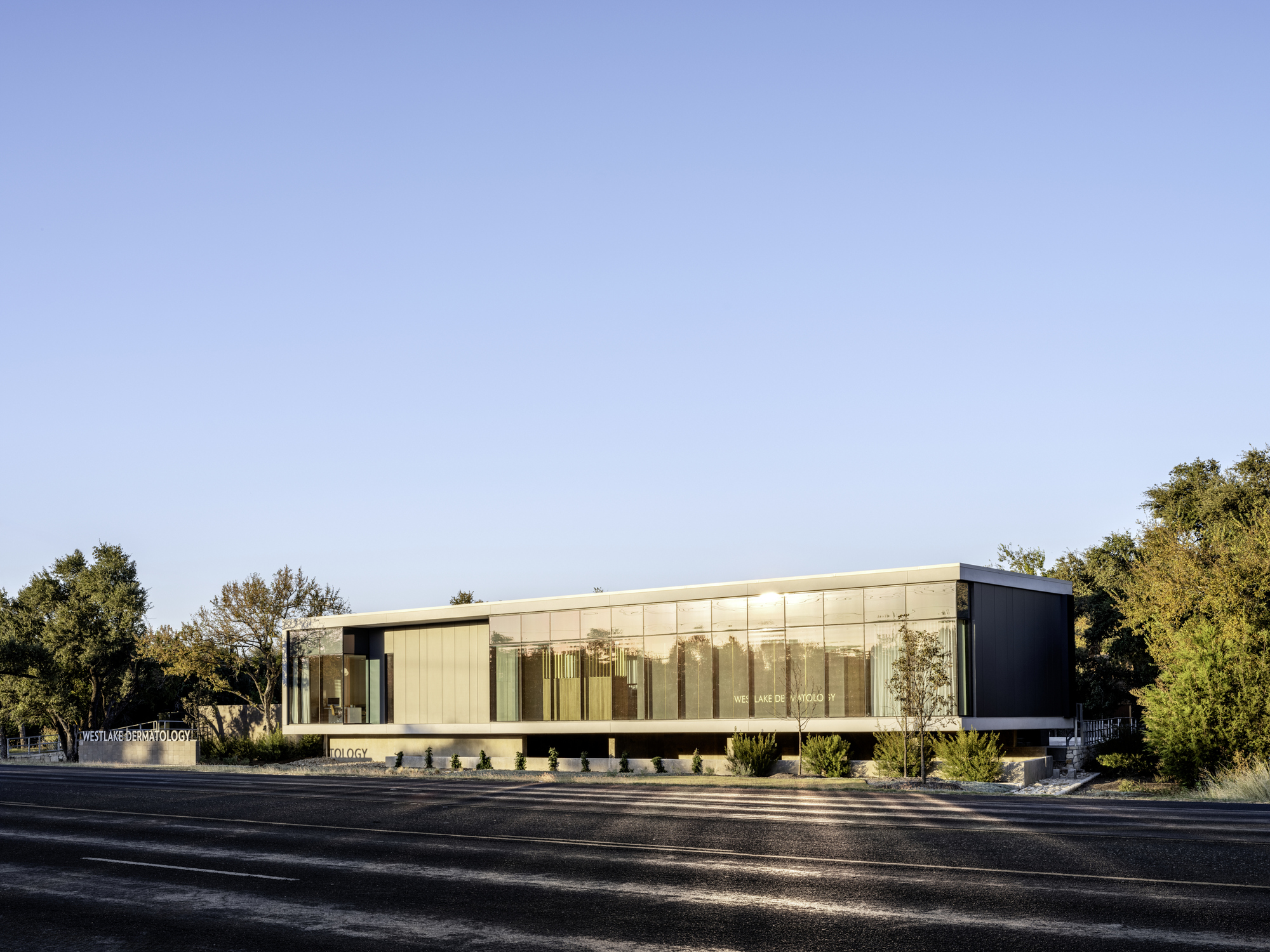 Street view of the long glass facade with vertical fins between dark side volumes
