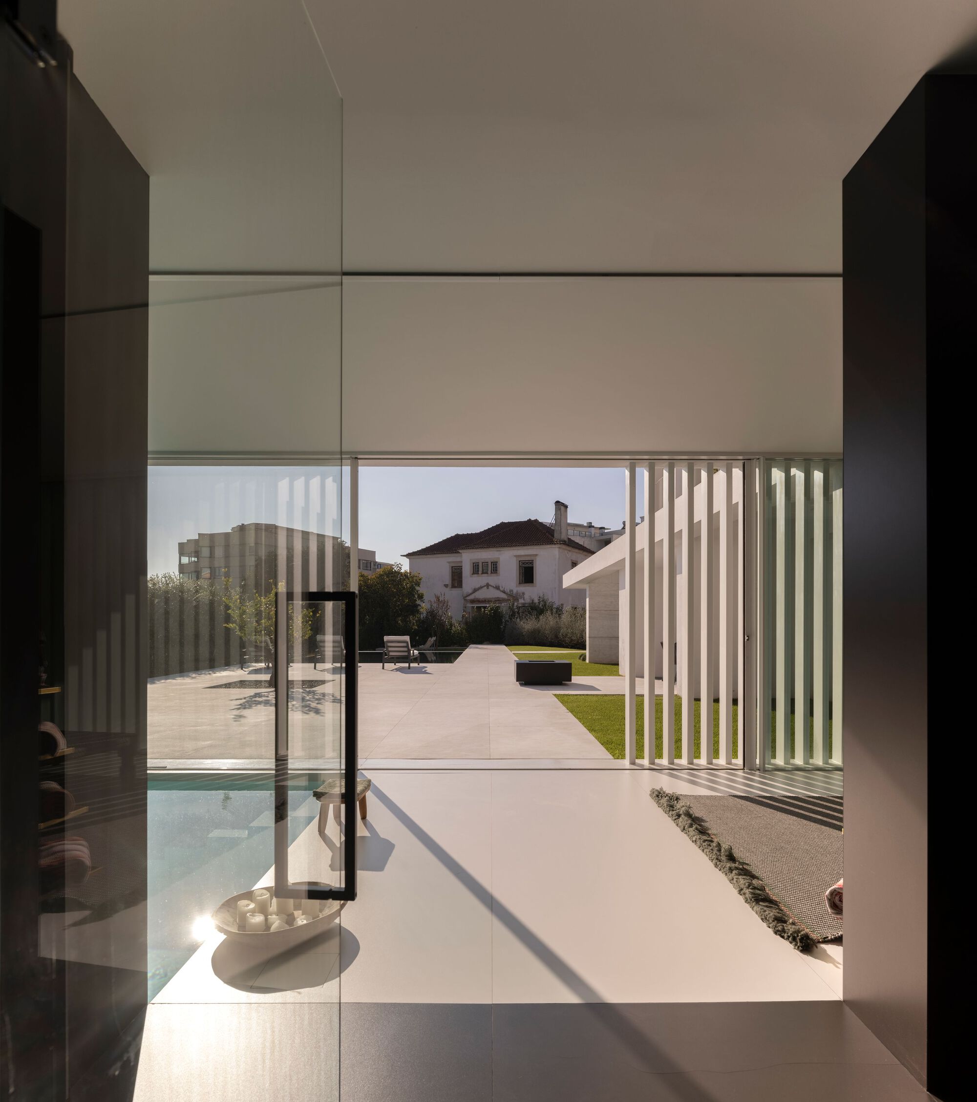 View from interior through floor-to-ceiling glass doors to the garden and slatted pergola beyond
