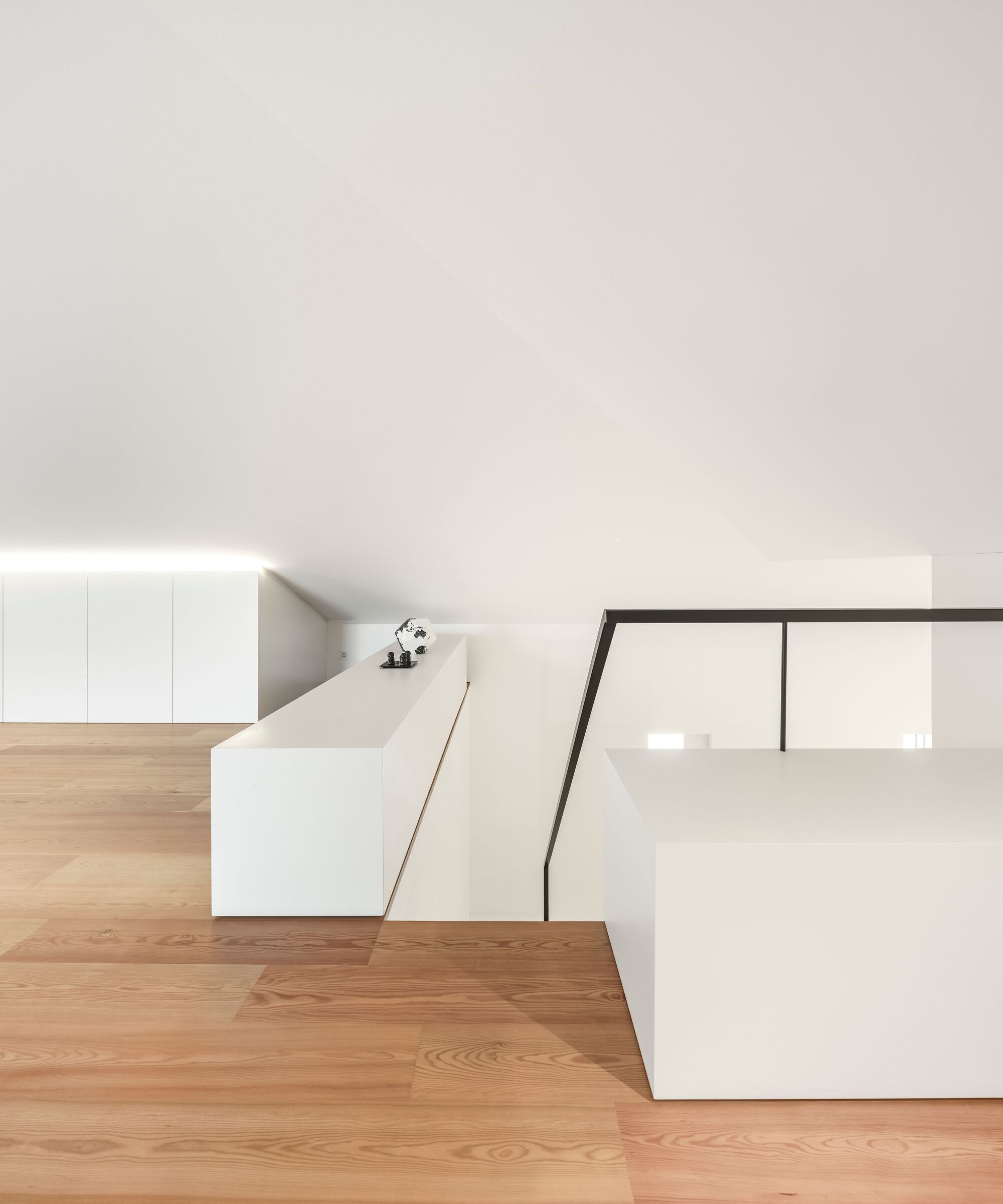 White kitchen island with angled glass balustrade overlooking the double-height space below