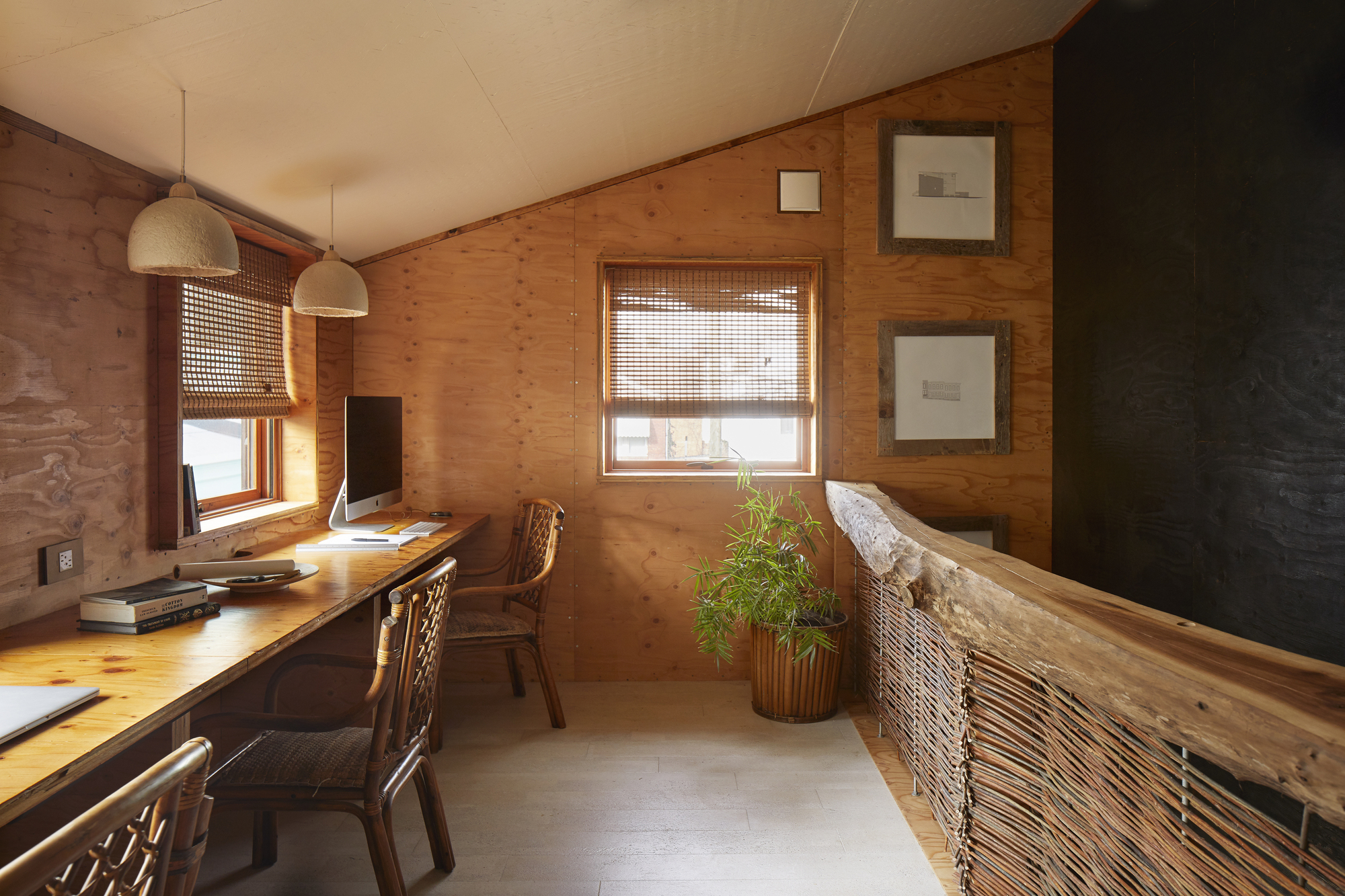 Timber-lined workspace with woven pendant lights and a potted plant in afternoon sunlight