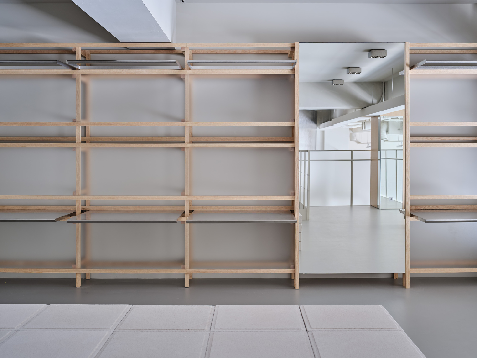 Timber shelving system with frosted glass lower panels along a gray tiled floor