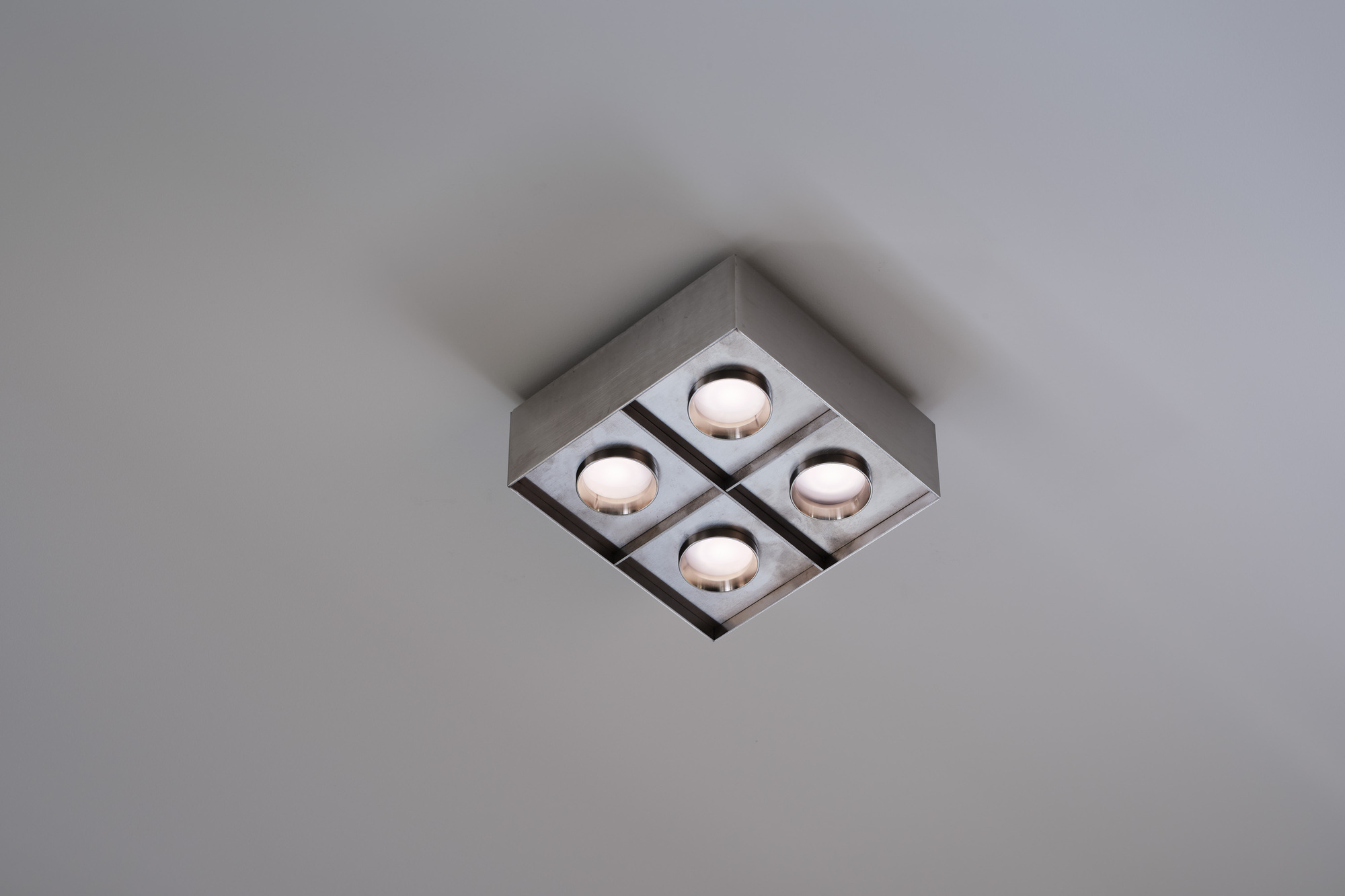 Square ceiling fixture with four recessed lamps in a brushed metal housing