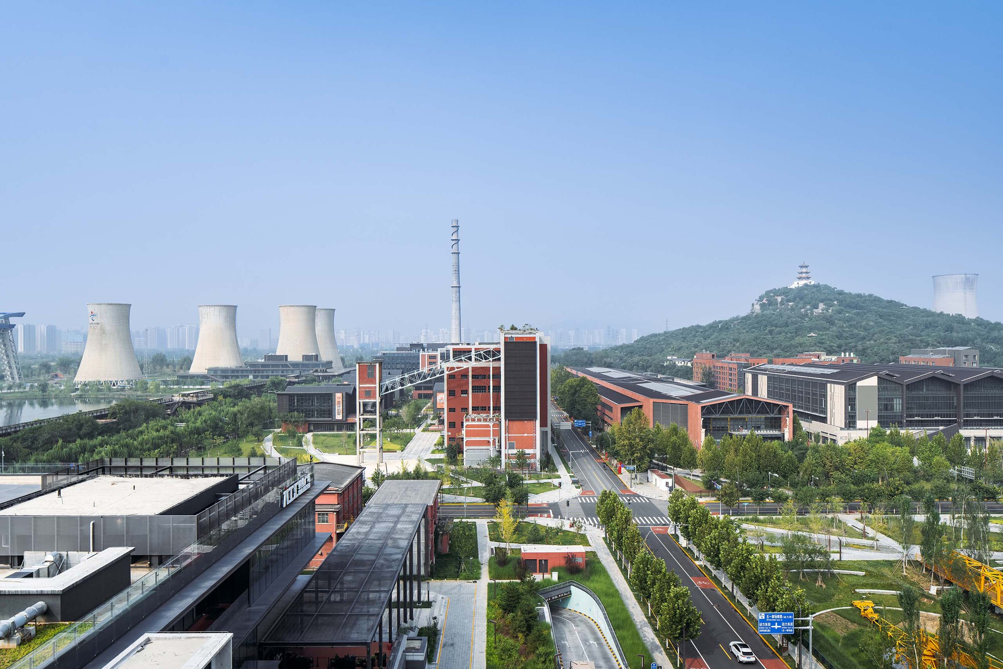 Aerial view of the campus with red brick towers, green boulevards, and cooling towers in the distance