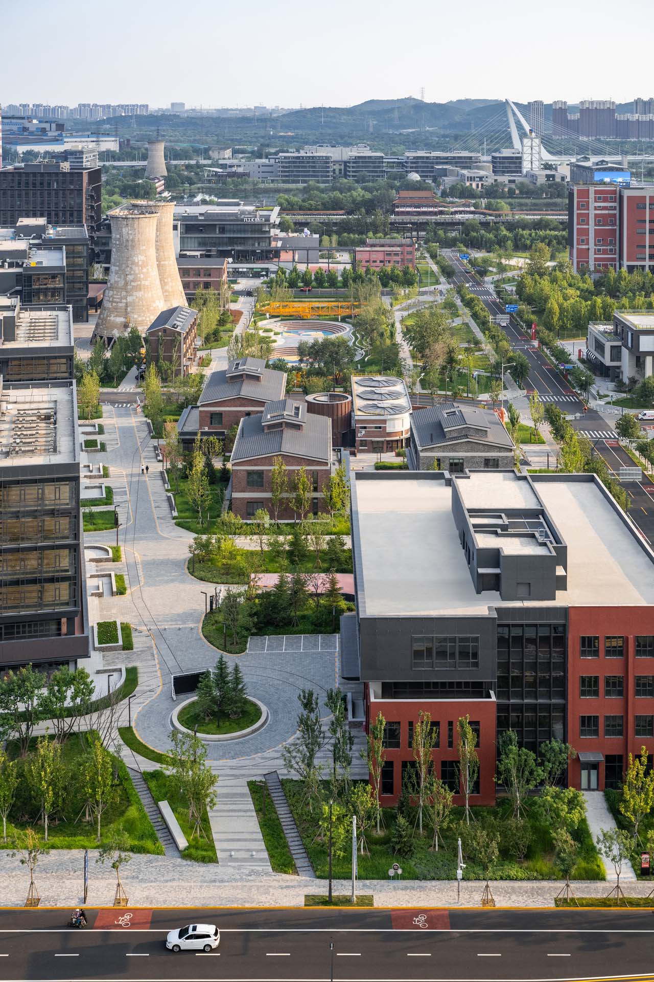 Elevated view of the tree-lined campus streets with red brick buildings and industrial structures beyond