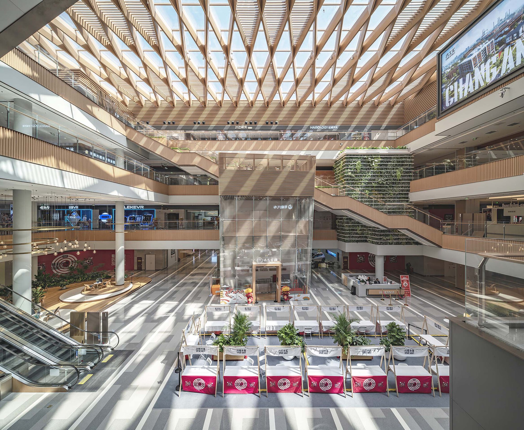 Multi-story atrium with timber lattice skylight casting diagonal shadows across the terrazzo floor below