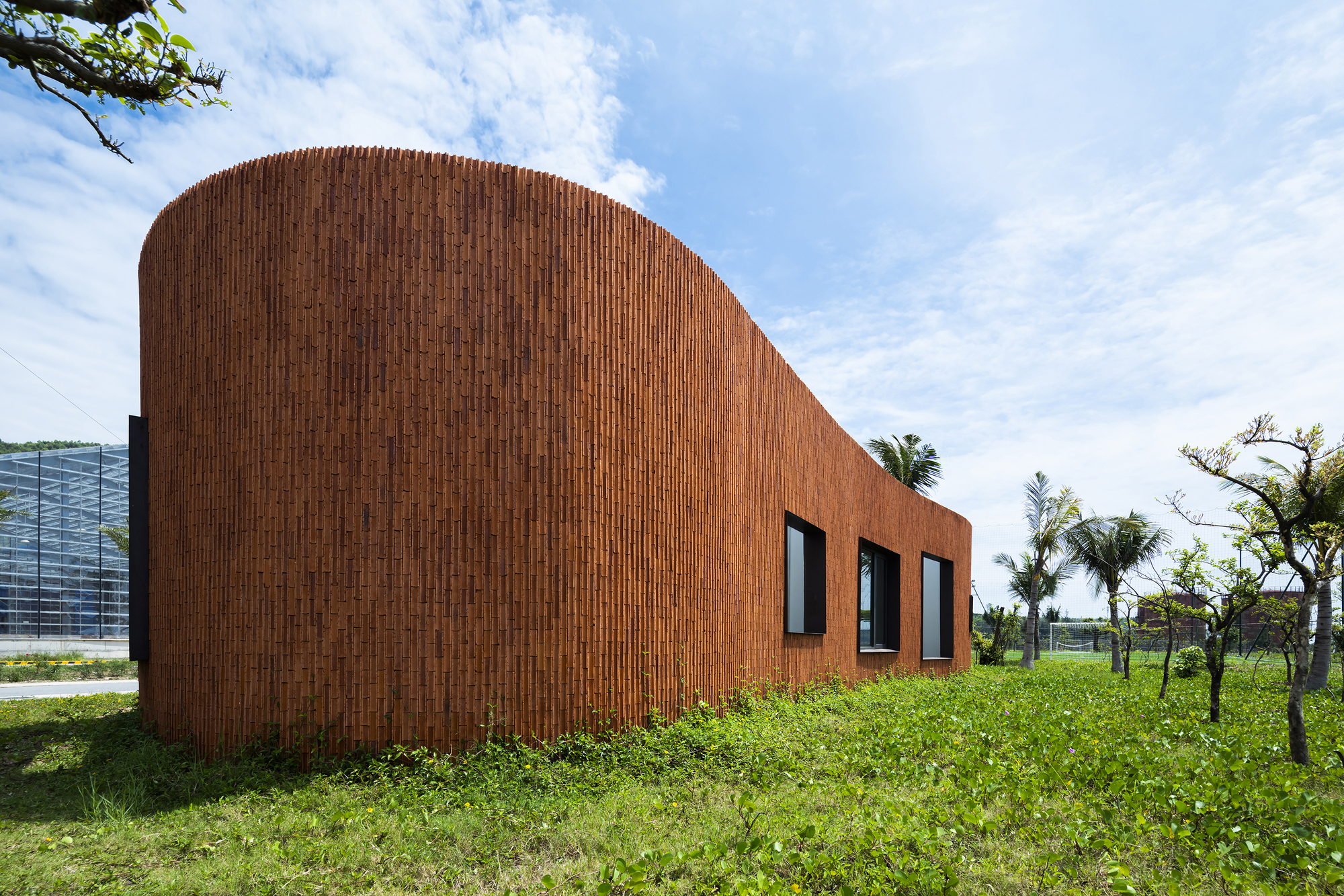 Vertical brick cladding wrapping the curved facade with three rectangular window openings