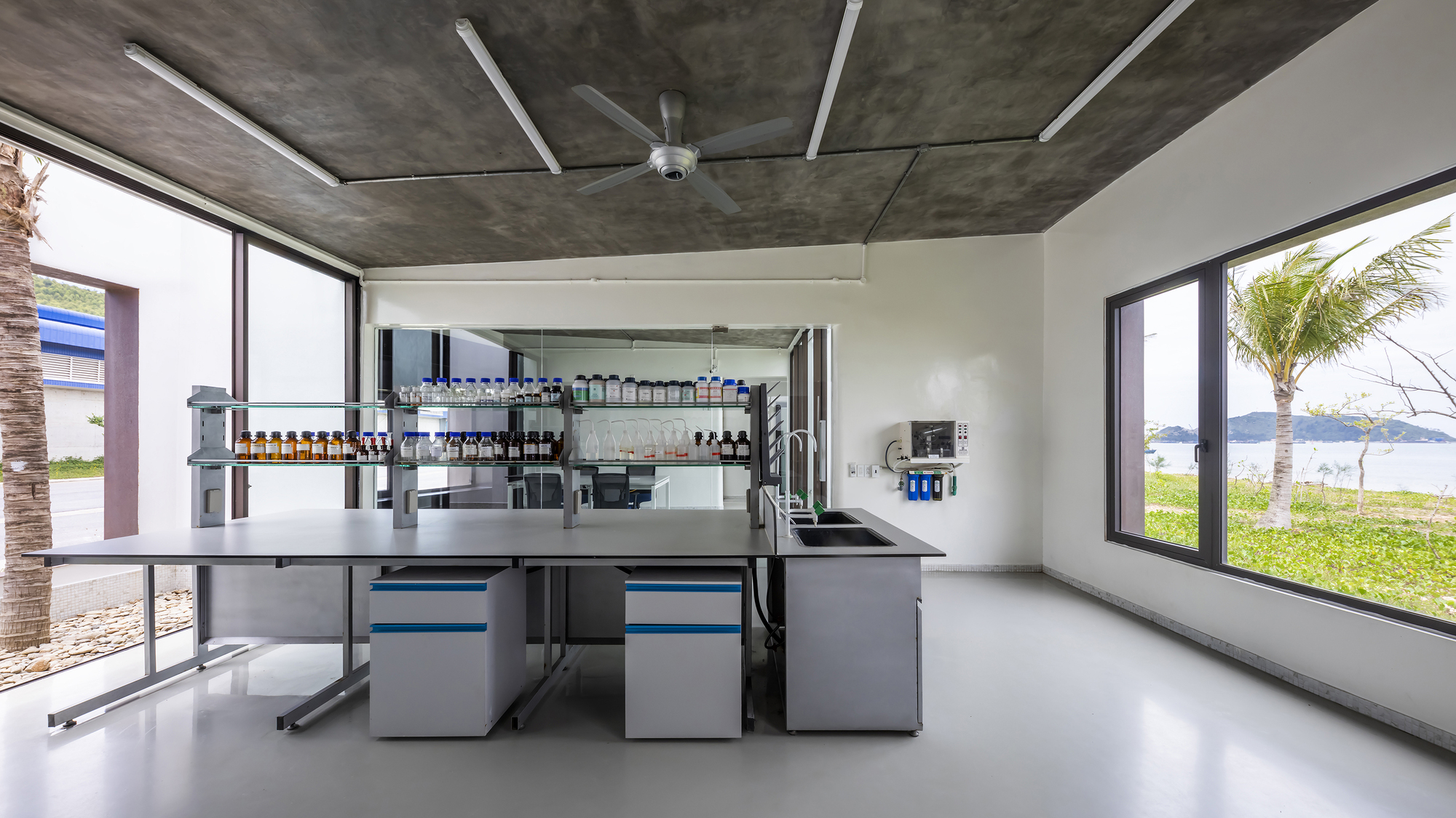 Laboratory interior with stainless steel workbenches and exposed concrete ceiling with ceiling fan