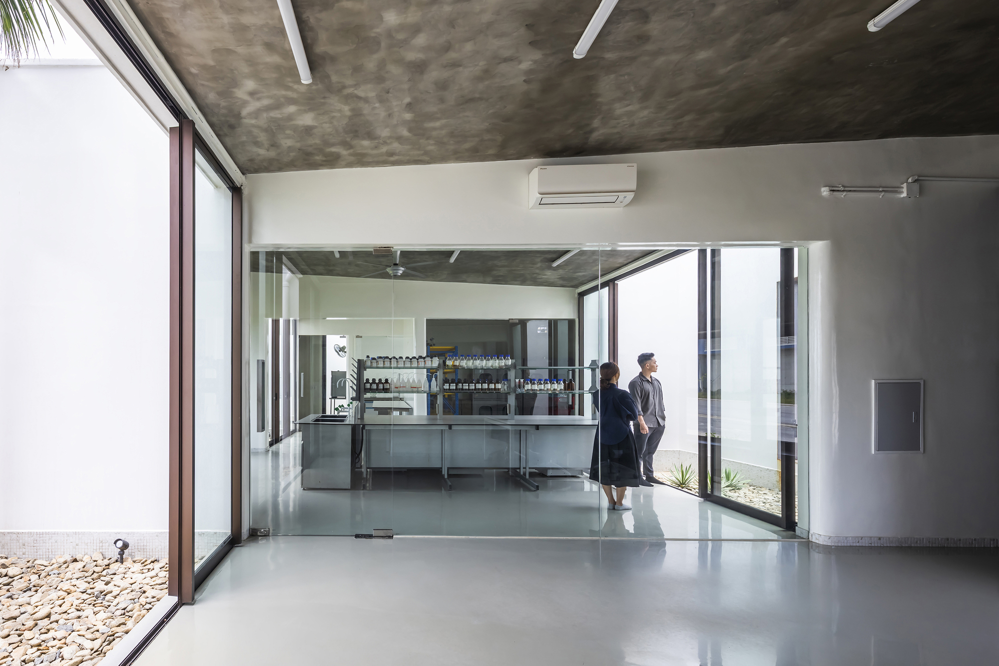 Interior corridor with polished concrete floor and glass-enclosed laboratory space with two figures in conversation