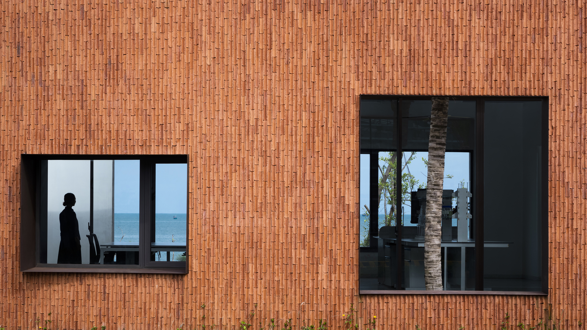 Exterior view of vertical terracotta brick facade with two offset window openings
