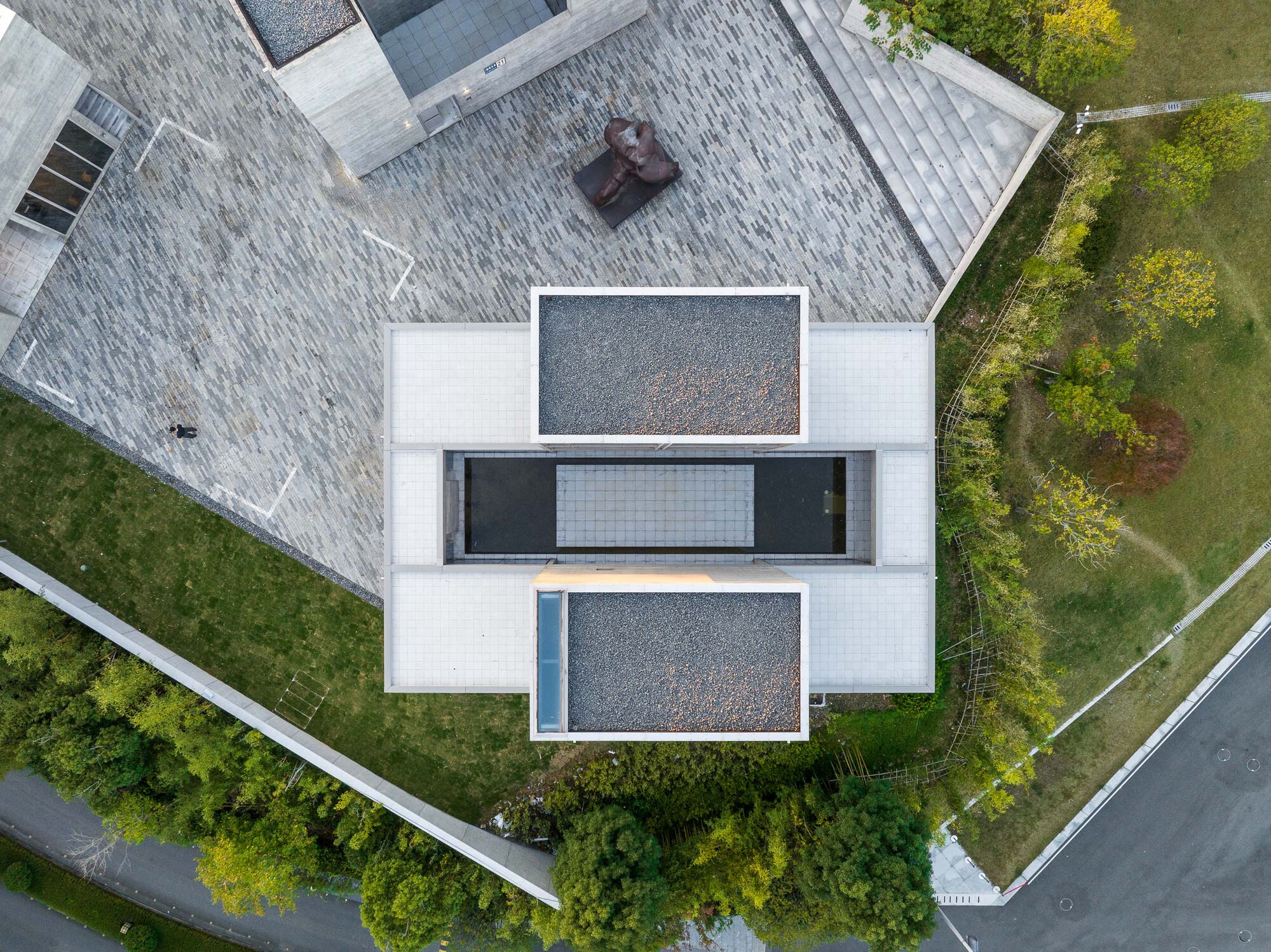 Drone view showing stacked terraces with gravel surfaces and glazed openings between shingled roofs