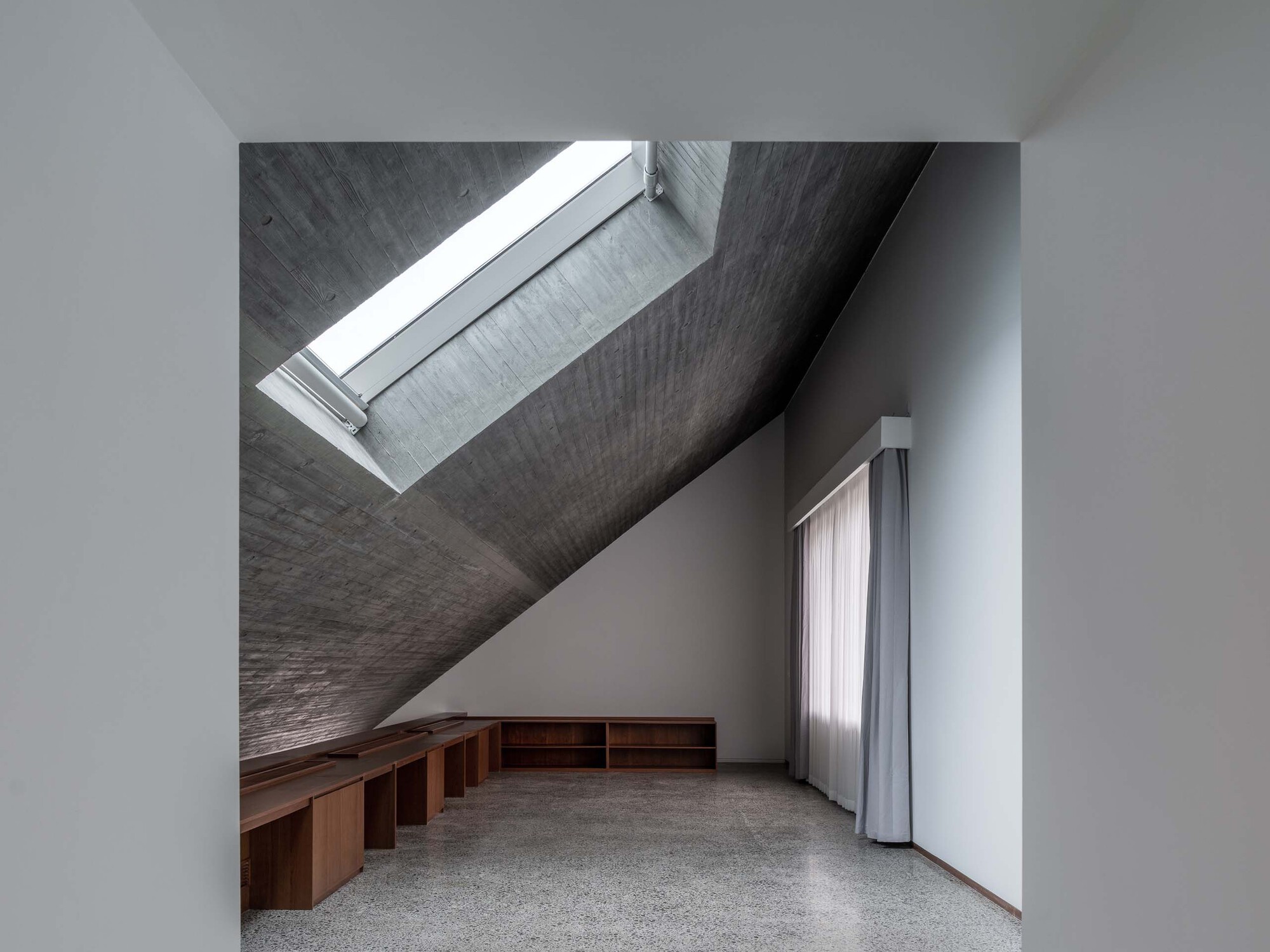 Attic room with dark timber ceiling, skylight, and built-in wooden storage below white walls