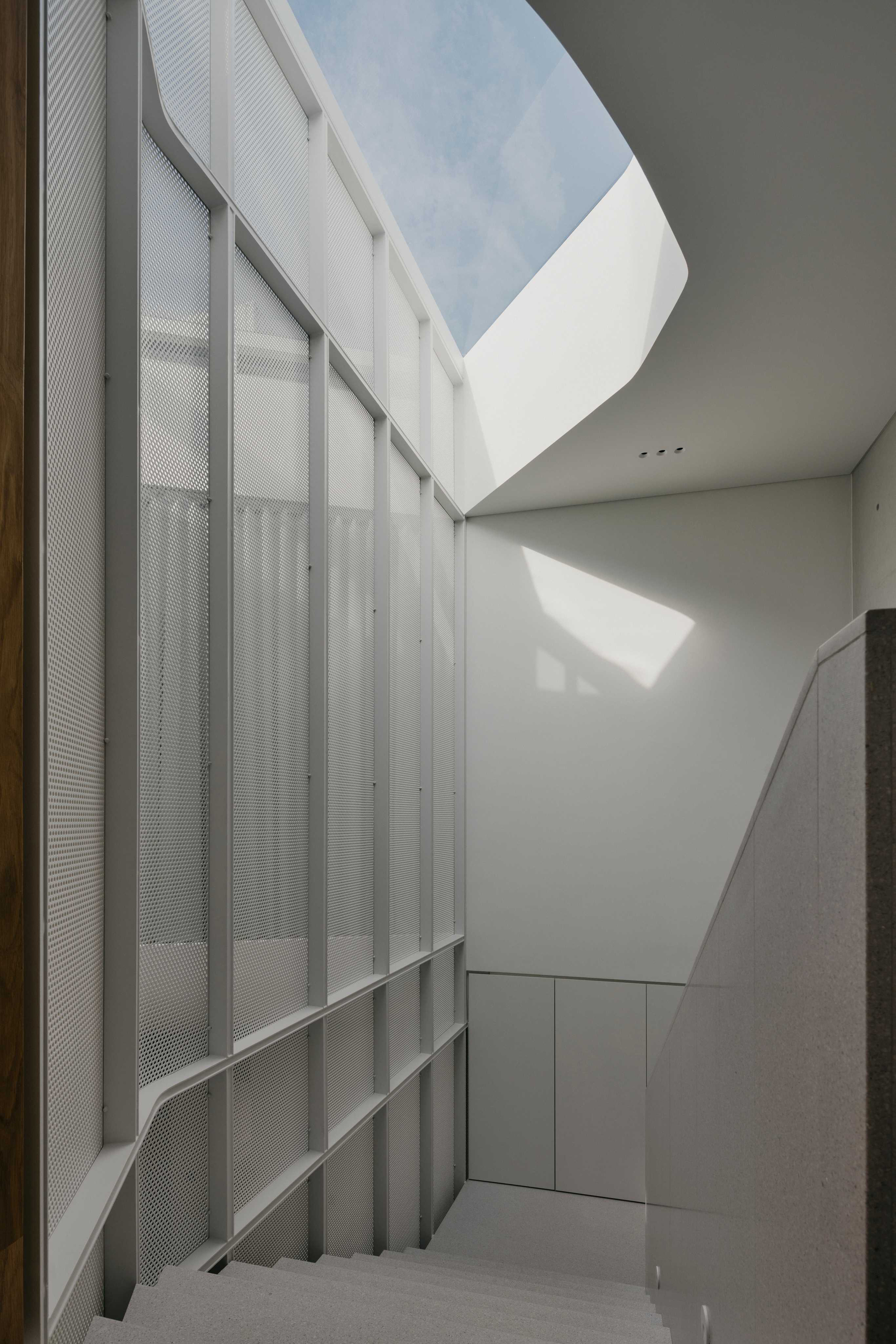 Interior courtyard with translucent perforated metal panels and an angular skylight opening to blue sky