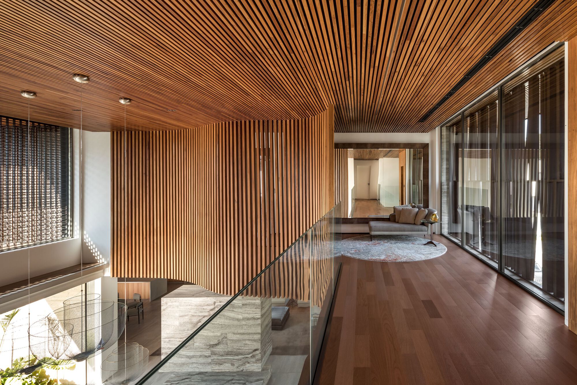 Upper-level walkway with timber slat ceiling and walls overlooking the living space below