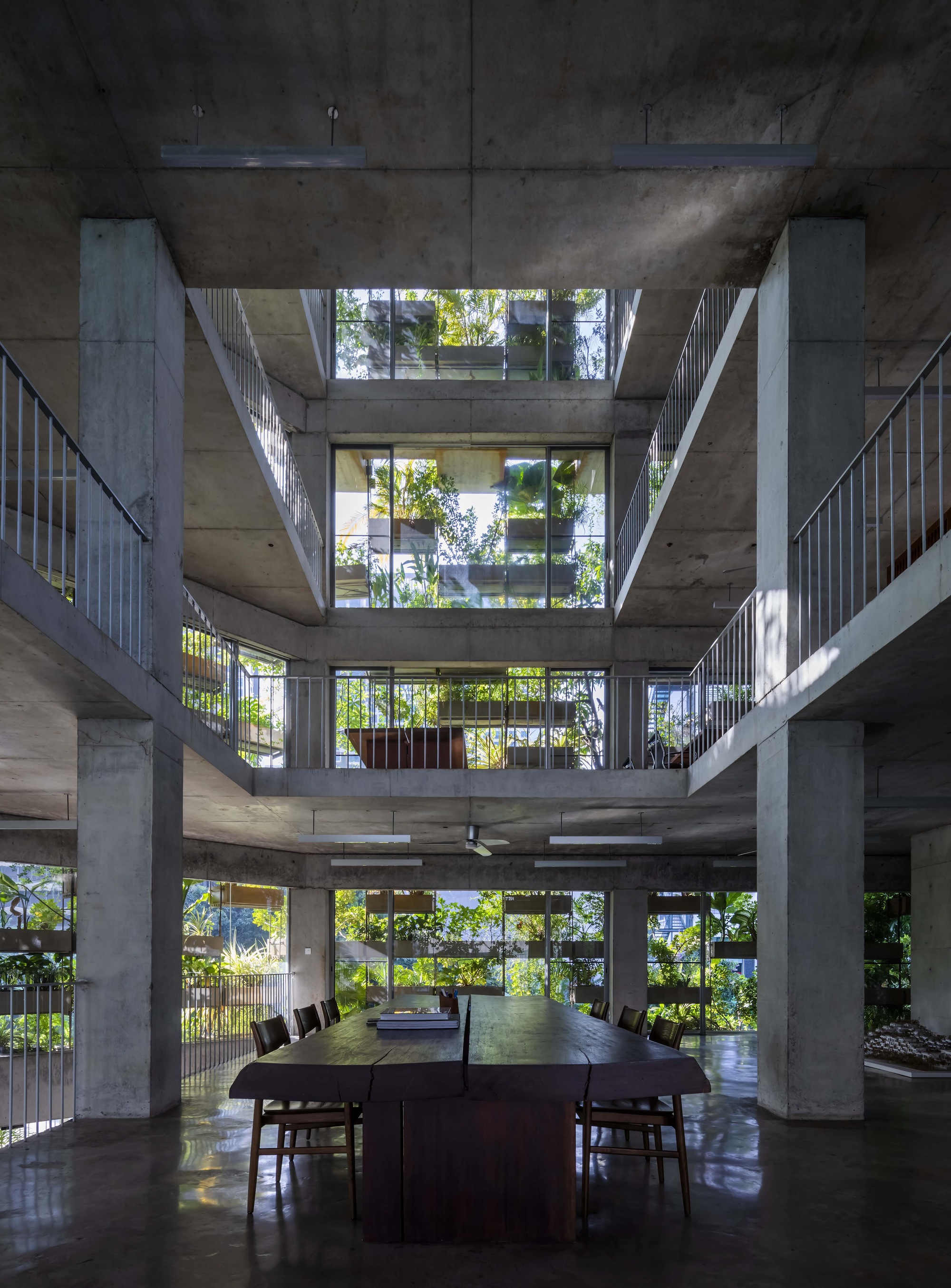 Central void looking up through stacked concrete slabs and metal railings with planted terraces above