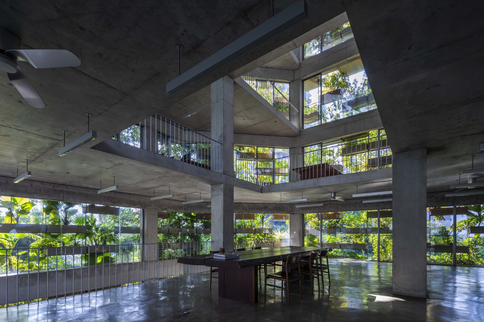 Open-plan interior with concrete columns and slabs framing planted balconies beyond full-height glazing