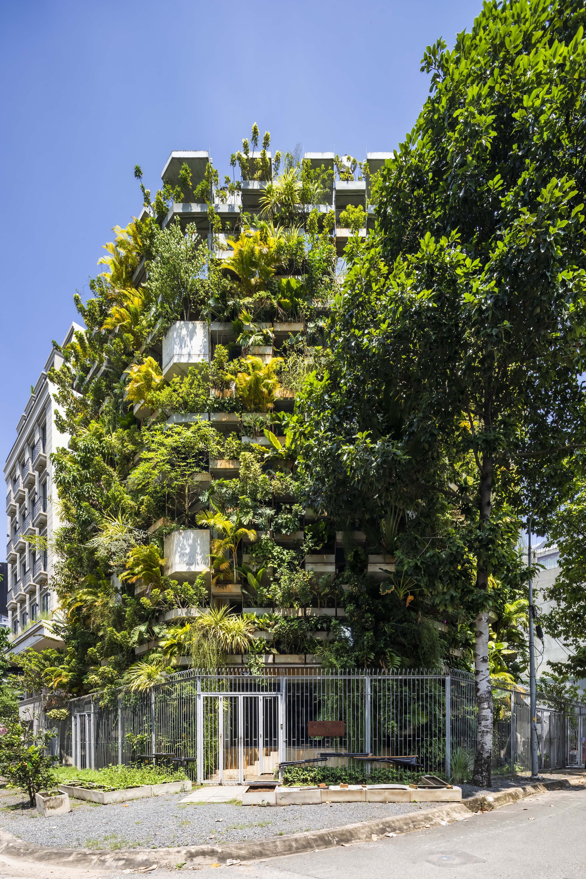 Street elevation showing the planted tower behind a low perimeter fence and entry gate