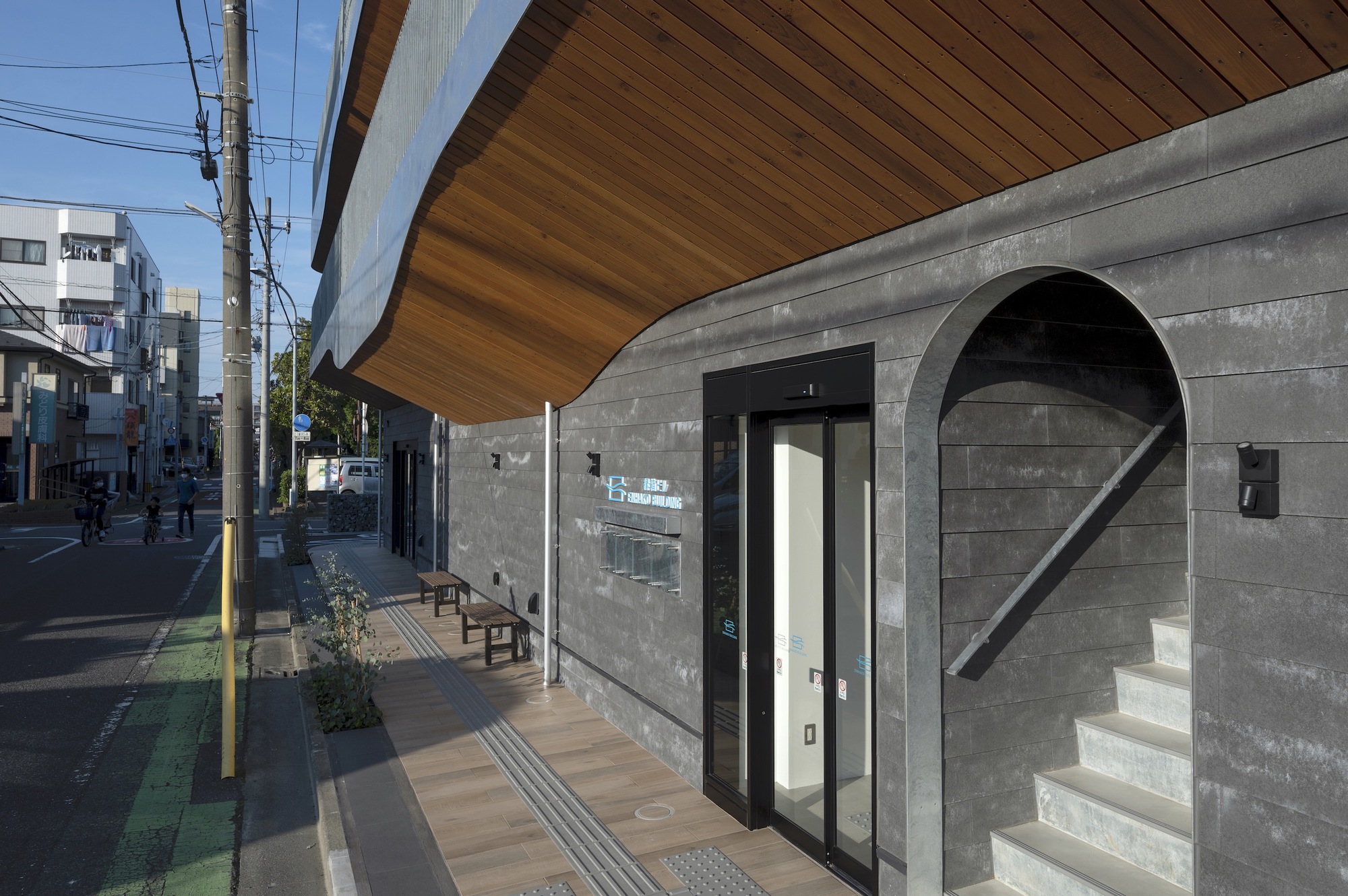 Street level entrance with concrete block wall, arched opening with stair, and overhanging wood soffit